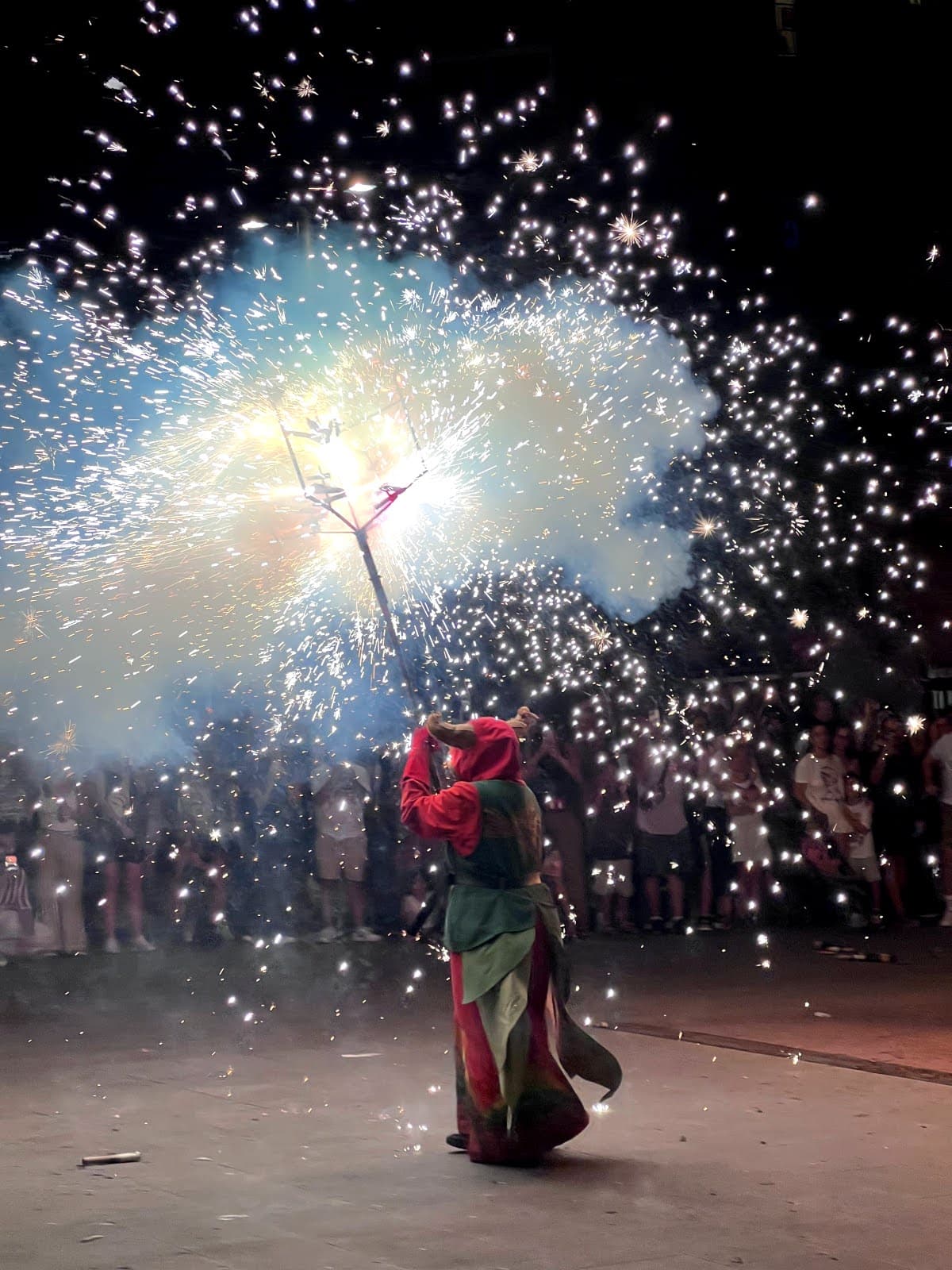 A performer dressed as a devil spinning fireworks during a correfoc fire run in Barcelona at night.