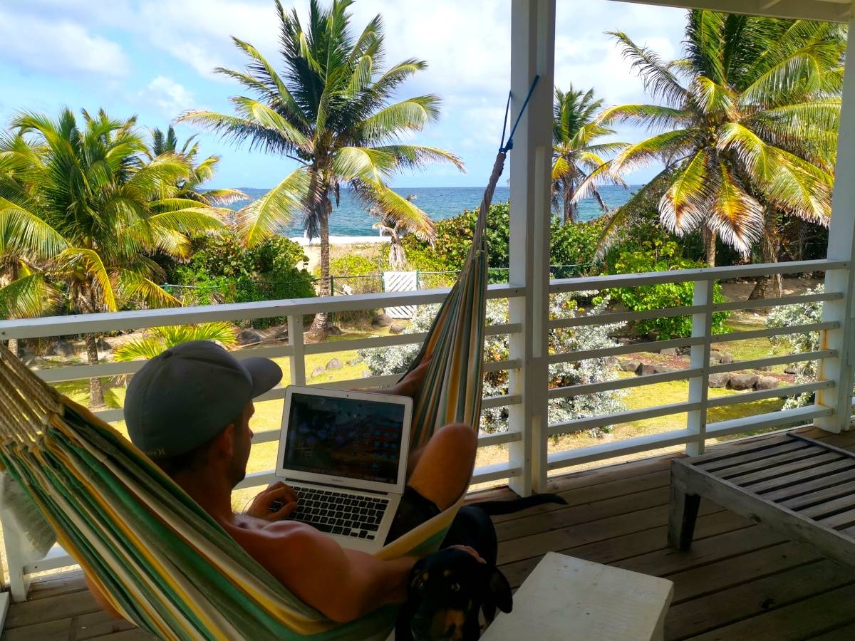 Allan sitting in a hammock with his laptop overlooking the ocean researching the best travel health insurances for digital nomads.