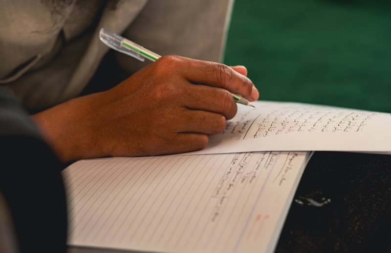 A person writing on a notebook with a pen