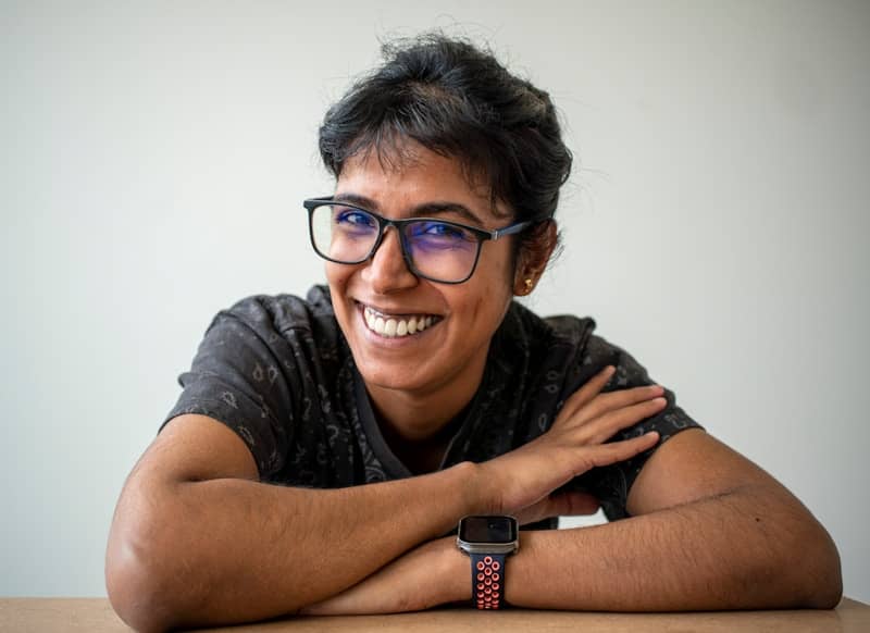 A smiling woman is wearing glasses and a watch.