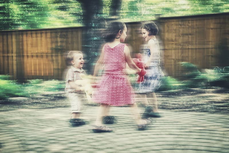 Children hold hands in a circle and laugh as they play