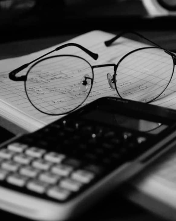 A computer desk with a keyboard, mouse and glasses on it