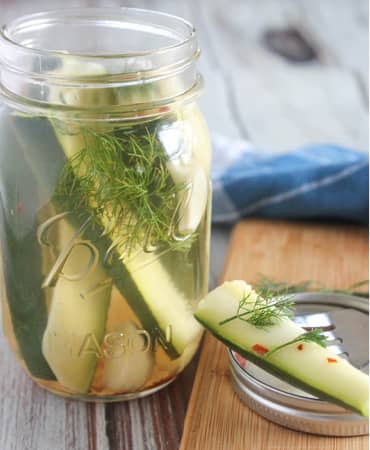 a mason jar filled with spears of zucchini and dill