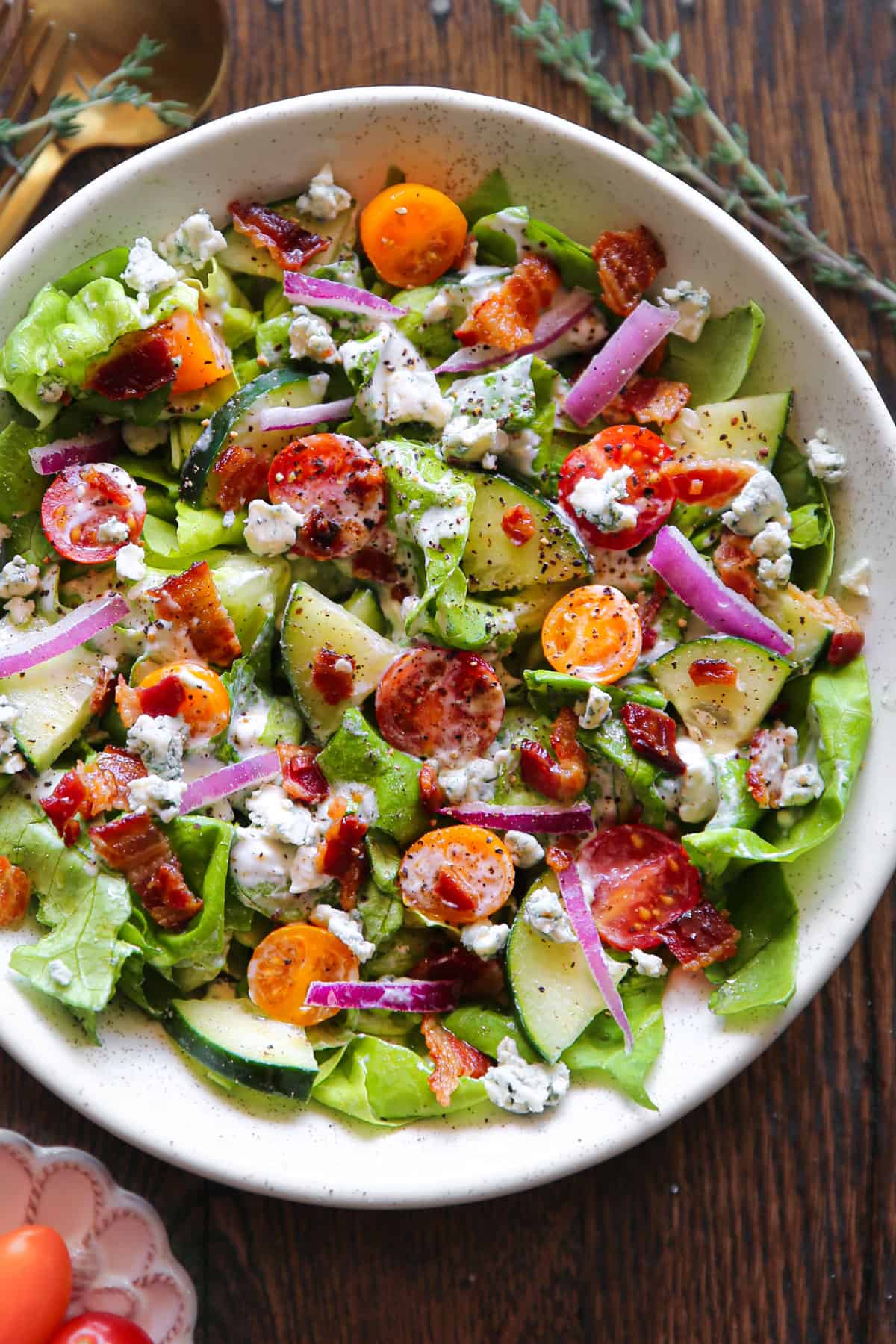 Tomato Cucumber Lettuce Salad with Blue Cheese Dressing in a white bowl.