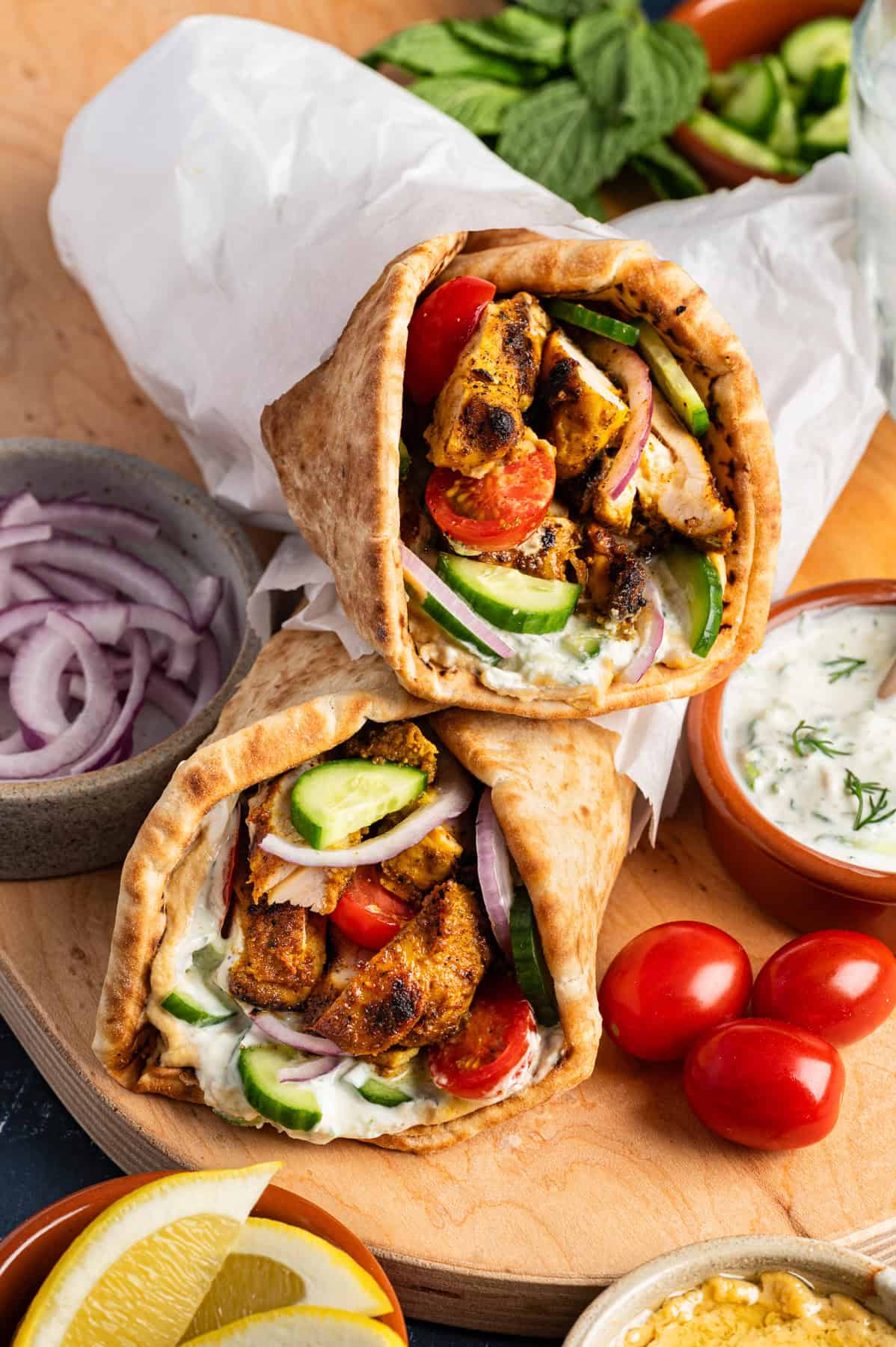 Chicken Shawarma Wraps (warm pita or flatbread, layered with hummus, tzatziki (or garlic sauce), cucumbers, tomatoes, red onion.