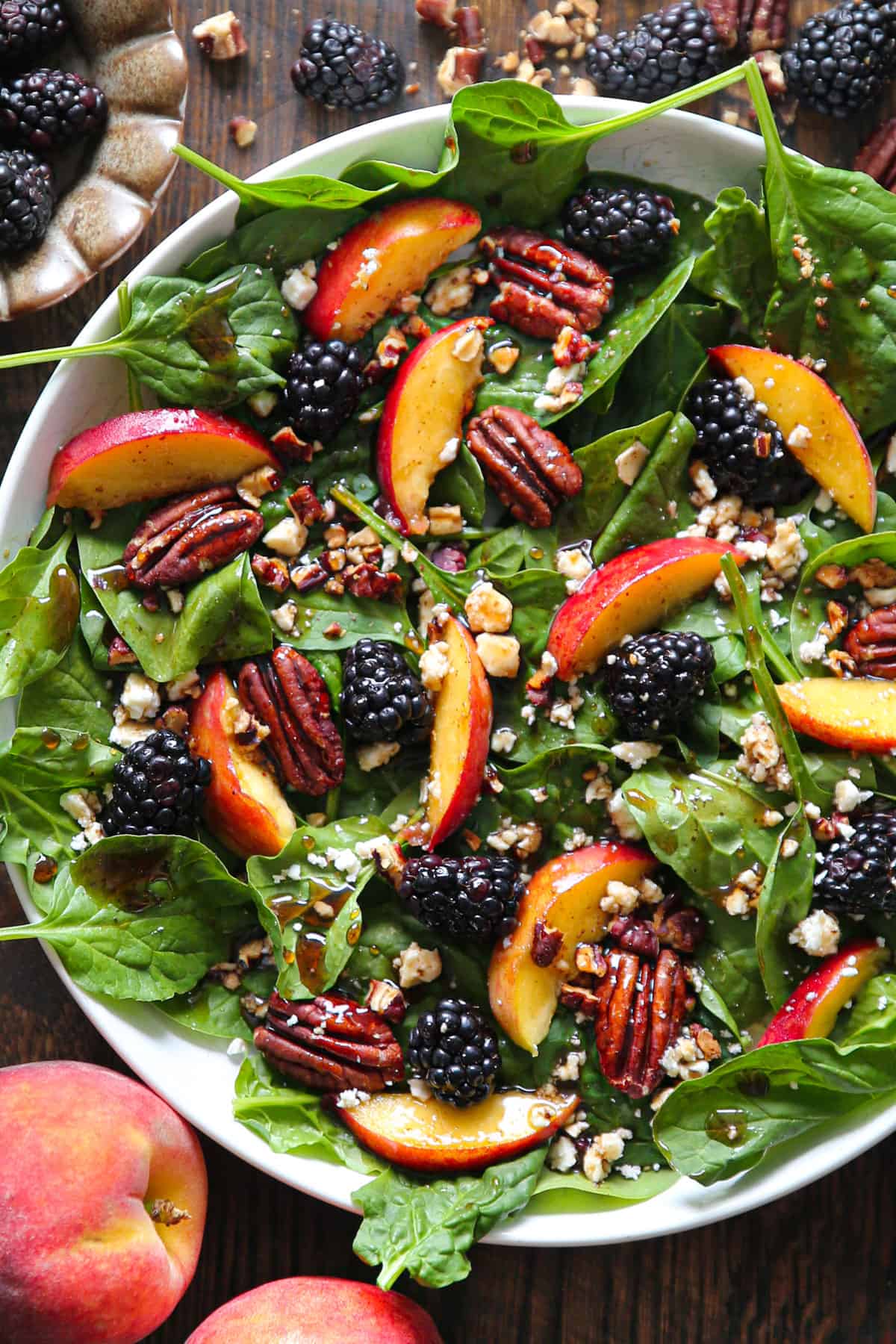 Summer Peach & Blackberry Salad with fresh greens, pecans, and balsamic dressing - in a white bowl.