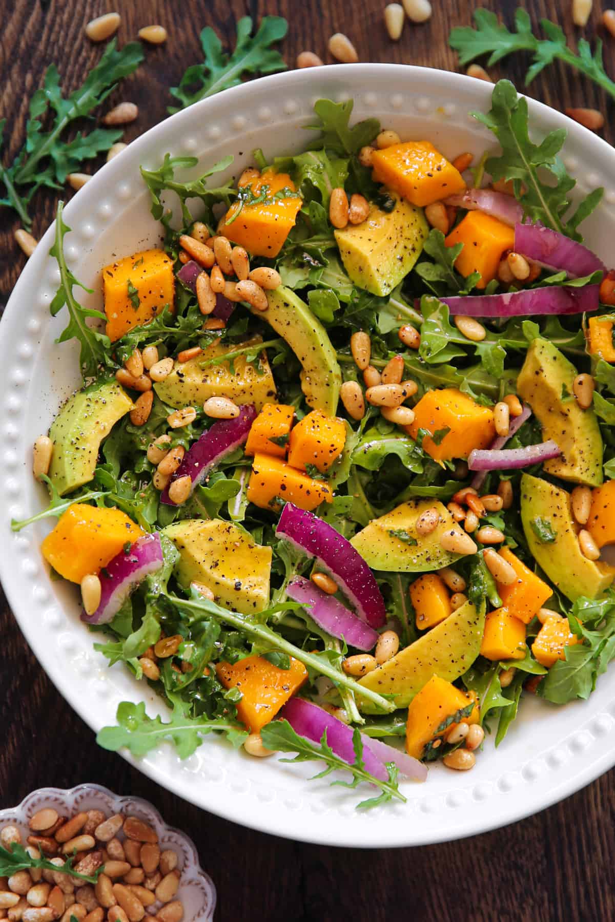 Avocado Mango Salad with Arugula, Pine Nuts, and Honey-Lime Dressing in a bowl.