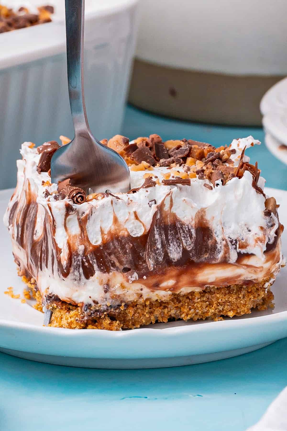 Chocolate Delight is a chilled layered dessert that combines a graham cracker crust with cream cheese, chocolate pudding, whipped topping, and toffee bits - a slice on a plate.