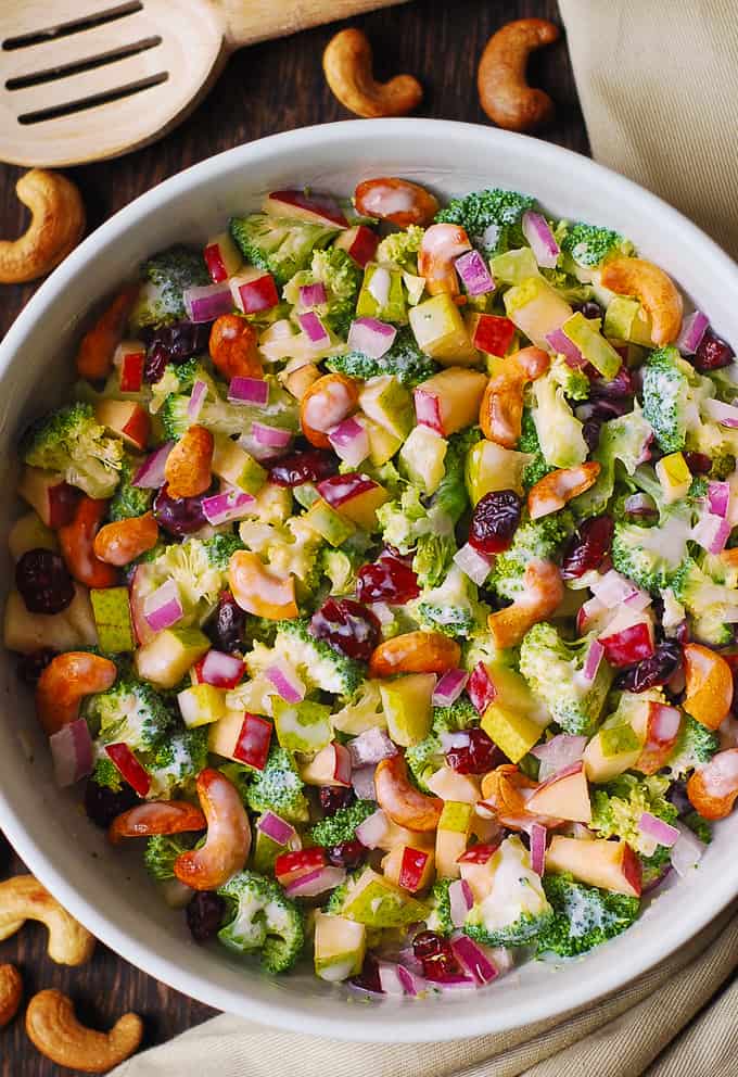 Creamy Broccoli Cashew Salad with Apples, Pears, and Cranberries in a white bowl.