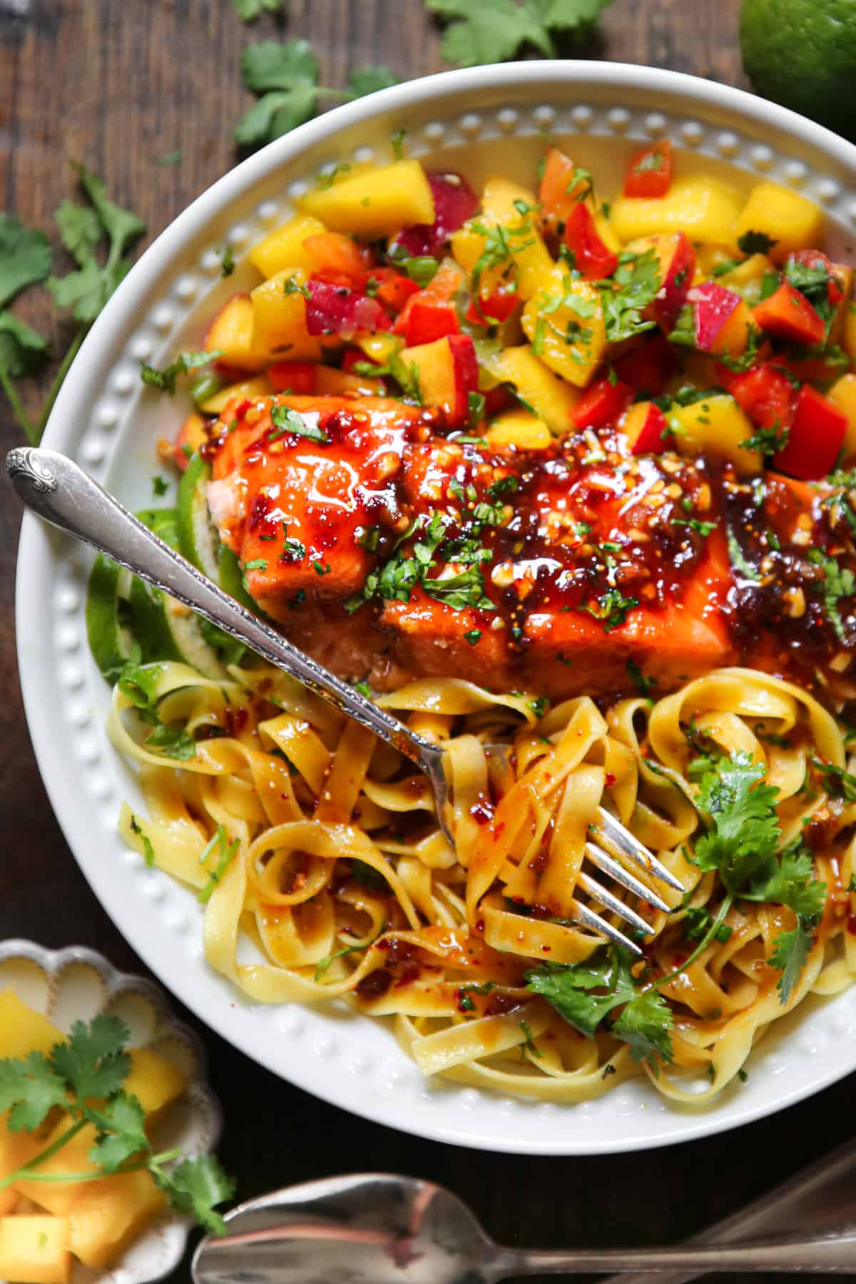 Asian Glazed Salmon with Egg Noodles and Mango Peach Salsa in a white bowl.
