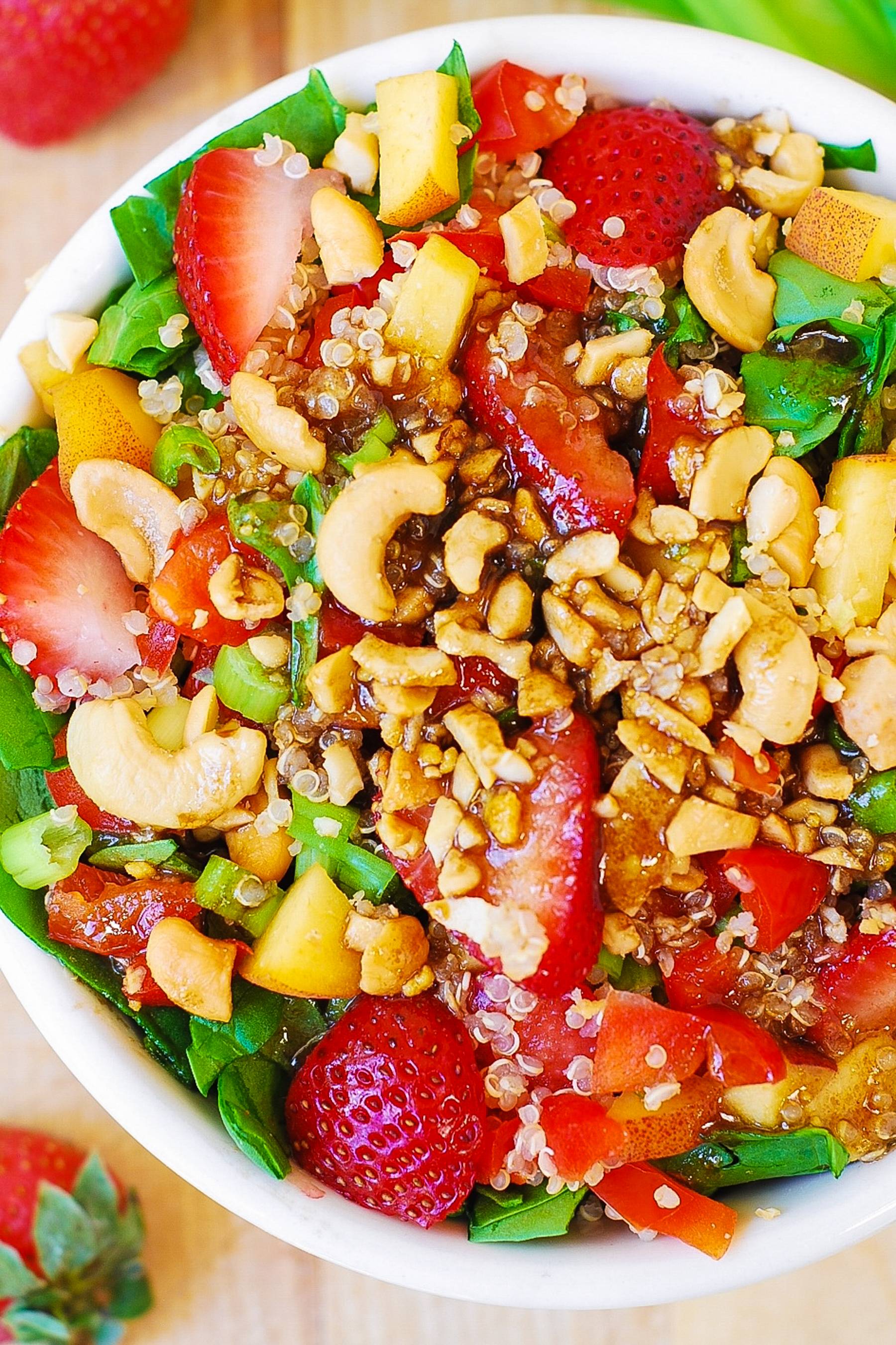 Strawberry Spinach Salad with Quinoa, Peaches, and Cashews in a bowl.