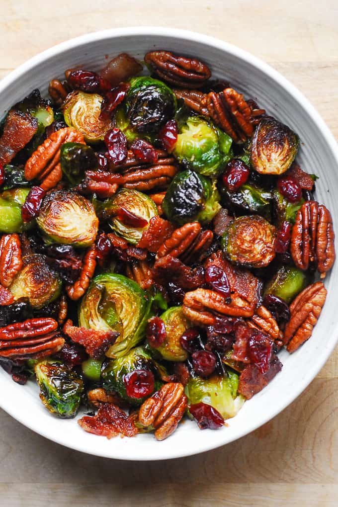Roasted Brussels Sprouts with Bacon, Toasted Pecans, and Dried Cranberries in a white bowl.
