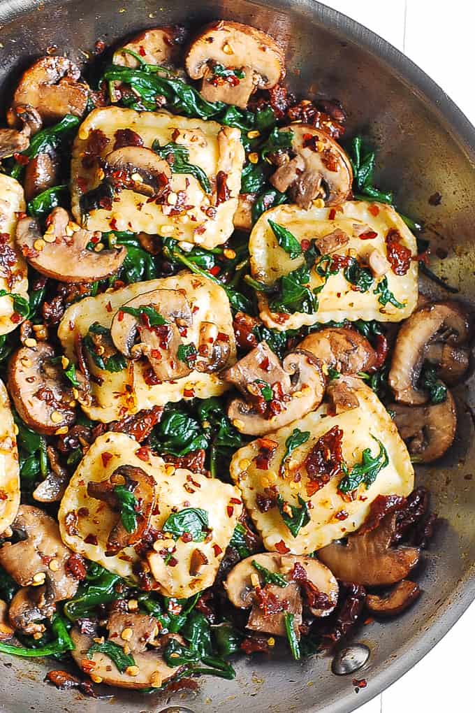 Mushroom and Spinach Ravioli in a stainless steel skillet. 