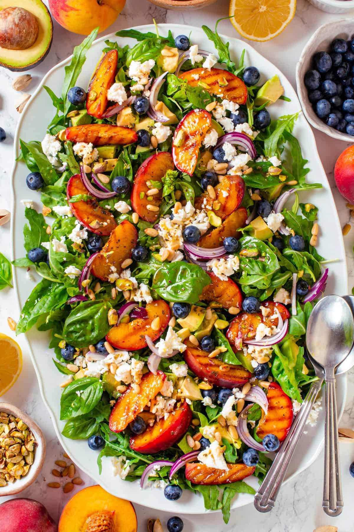 Grilled Peach Salad with Arugula, Blueberries, Avocado, Feta, and Nuts on a platter.