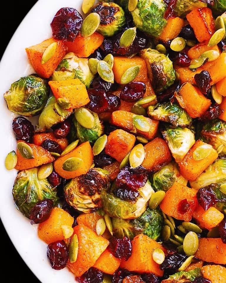 Roasted Brussels Sprouts Salad with Maple Butternut Squash, Pumpkin Seeds, and Cranberries on a white plate.