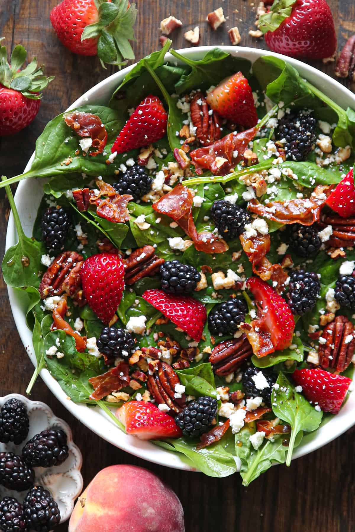 Strawberry & Blackberry Spinach Salad with Pecans, Feta, and Balsamic Glaze in a white bowl.