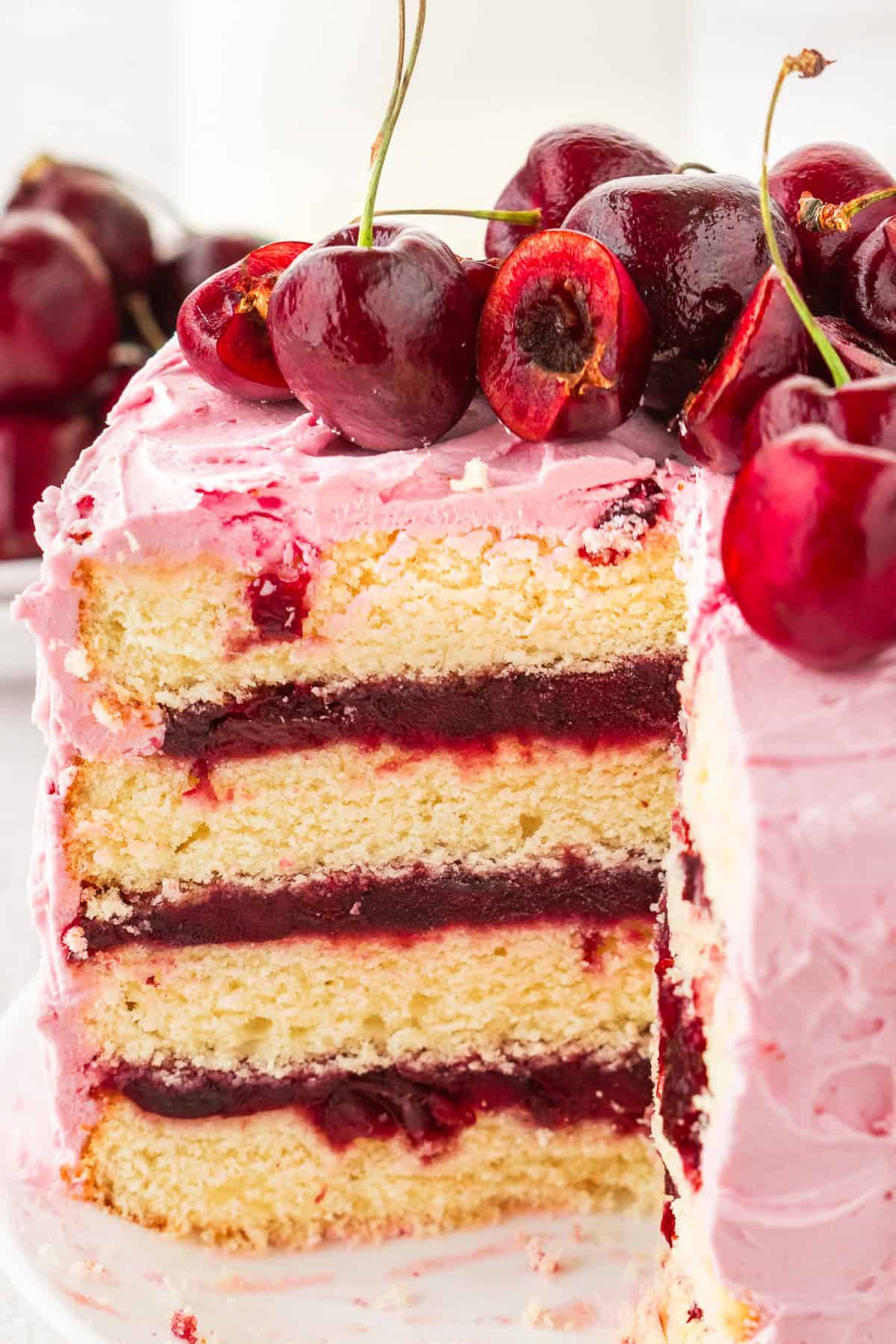 Cherry Layer Cake with Pink Frosting and Fresh Cherries on top.