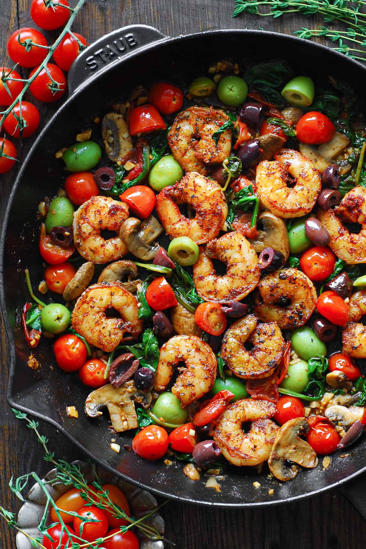 Mediterranean Shrimp with Olives, Tomatoes, Spinach, and Mushrooms in a cast iron skillet.