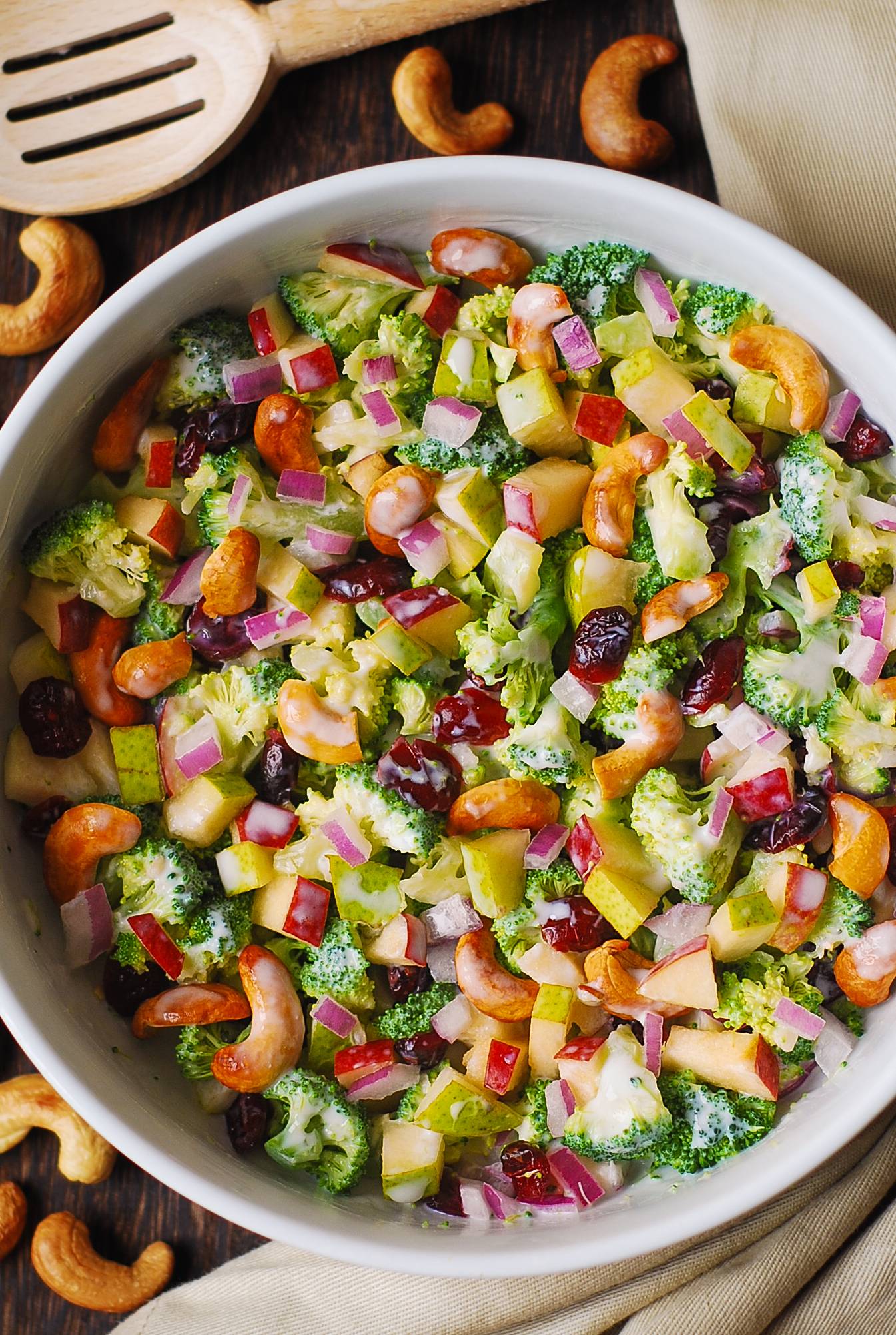 Creamy Broccoli Cashew Salad with Apples, Pears, and Dried Cranberries in a white bowl.