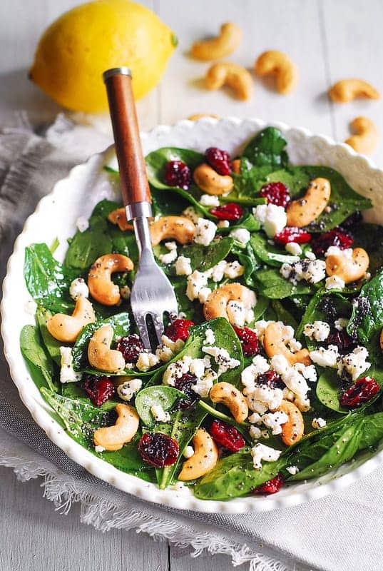 Cranberry Spinach Salad with Cashews and Goat Cheese in a bowl.