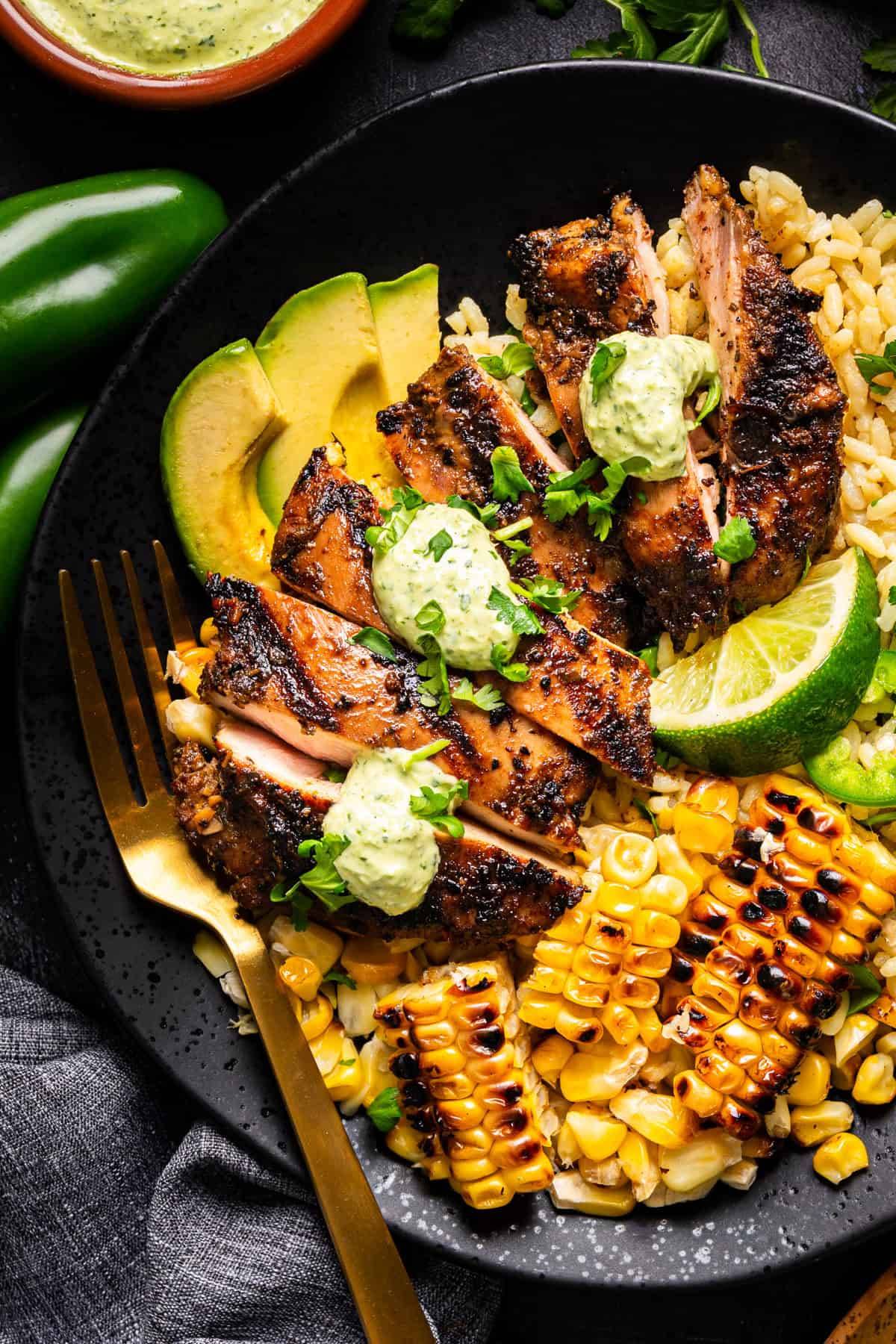 Grilled Peruvian Chicken with Cilantro Green Sauce on a black plate.
