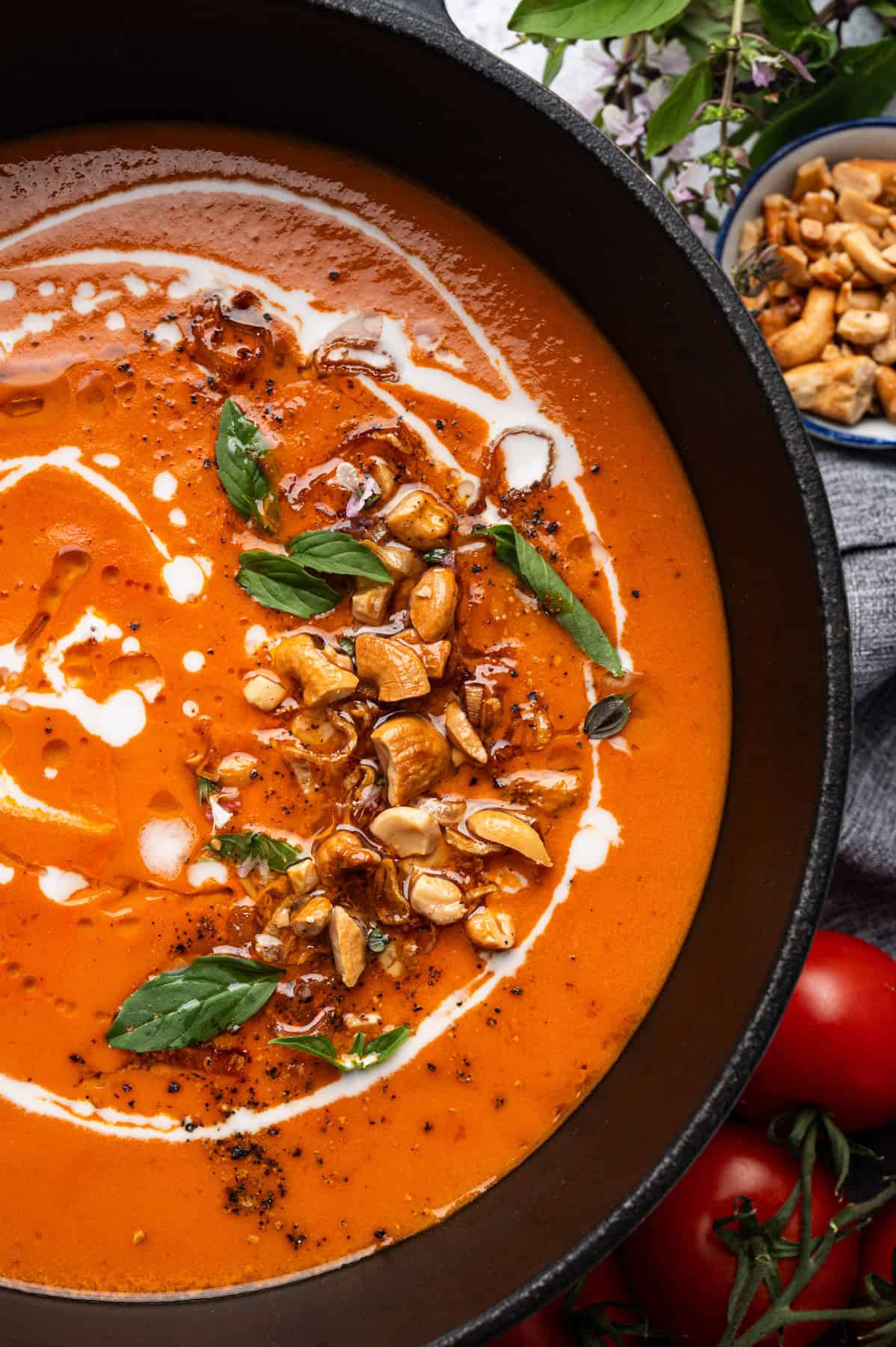Creamy Tomato Soup with crispy shallots, toasted cashews, and basil - in a soup pot.