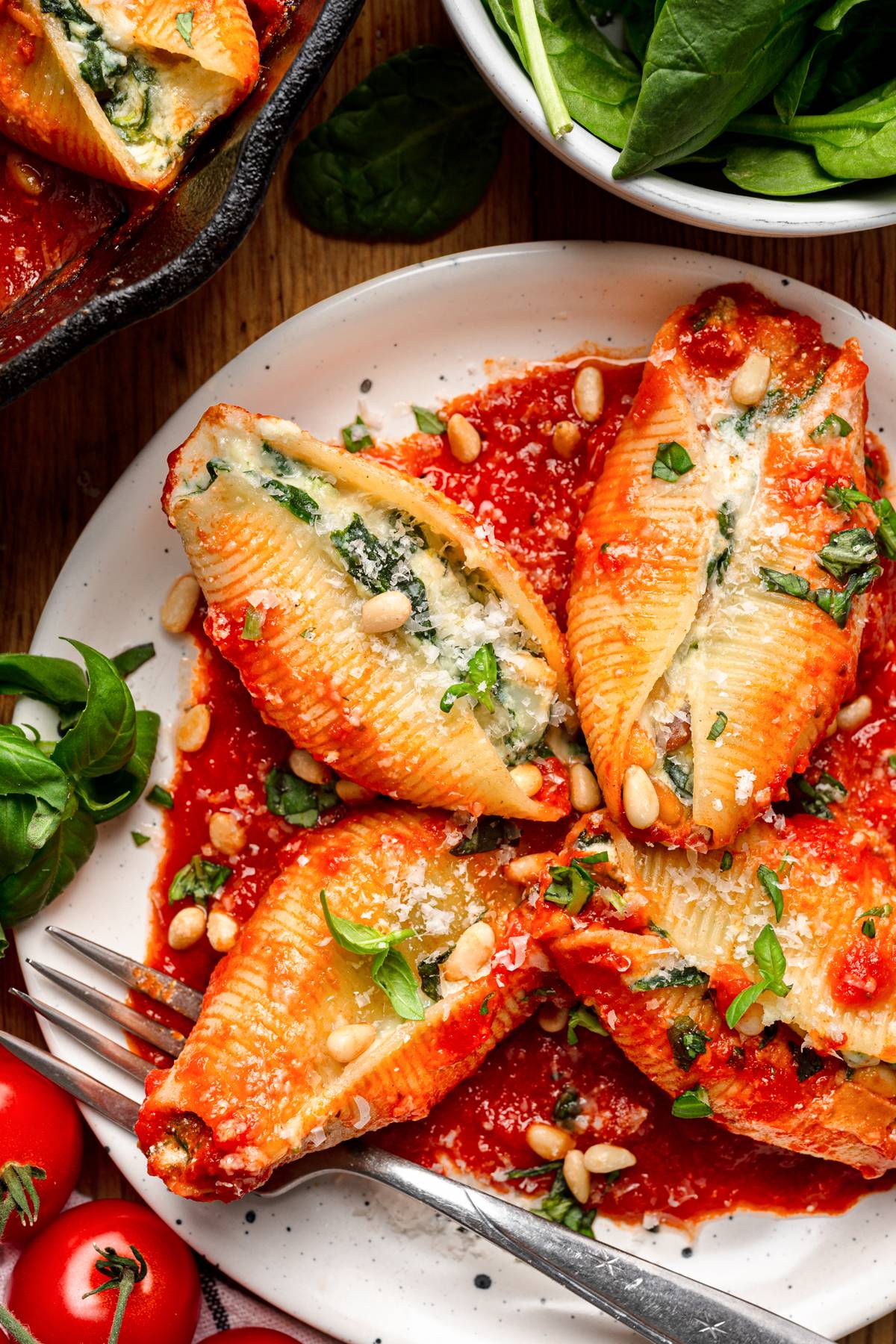 Spinach and Ricotta Stuffed Shells (with mozzarella, parmesan, tomato sauce, and pine nuts) on a white plate.