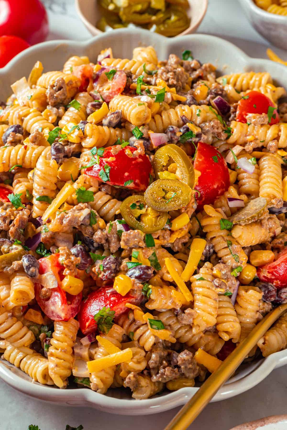 Cowboy Pasta Salad (with seasoned beef, corn, black beans, cheddar, bacon, and jalapeños in a tangy BBQ-mayo dressing) in a bowl.