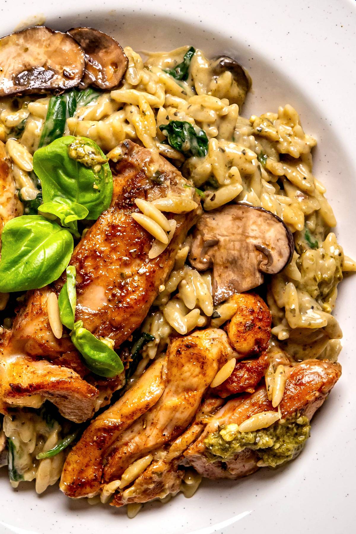  Creamy Pesto Chicken Orzo with Mushrooms and Spinach - on a white plate.