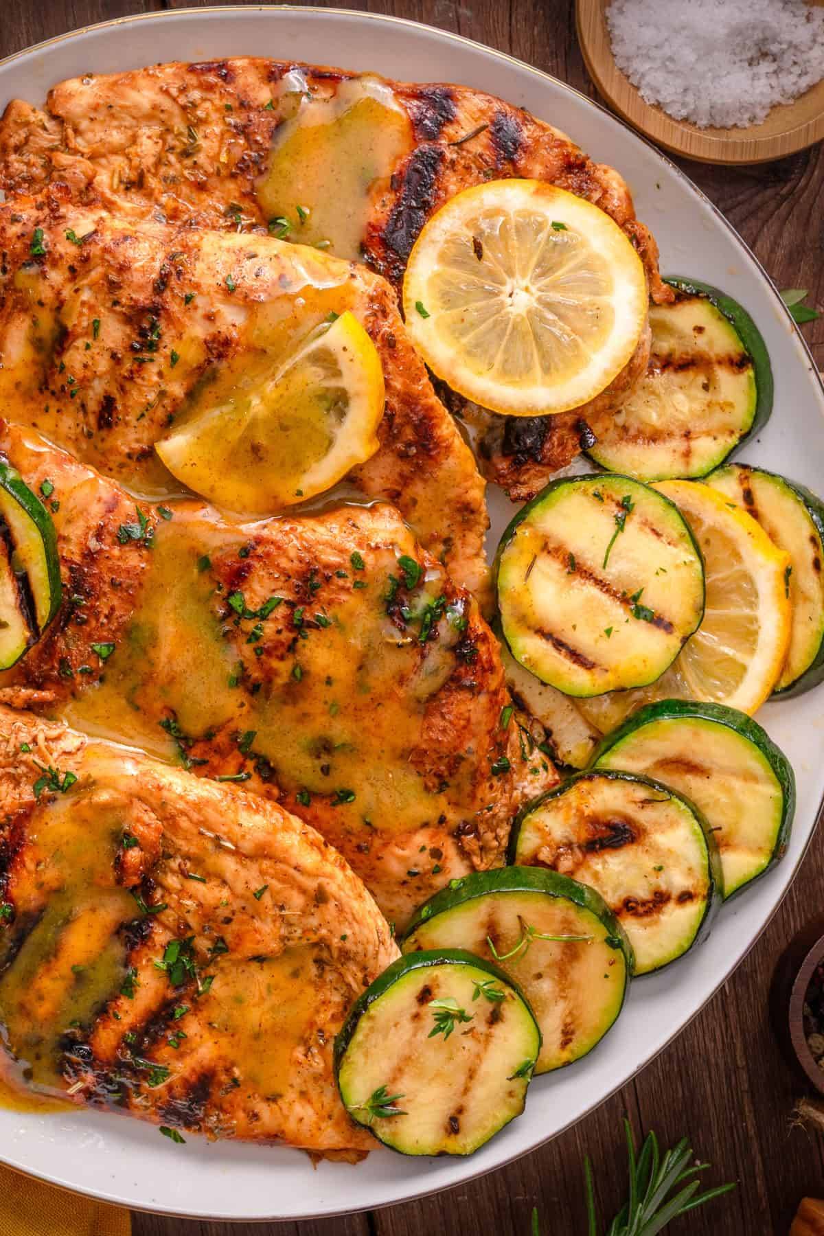 Grilled Chicken and Zucchini with Honey-Mustard Lemon Sauce​ (chicken breasts marinated with lemon, garlic, honey, paprika, and herbs) on a white plate.