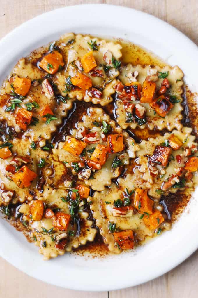 Butternut Squash Ravioli with Brown Butter Sauce and Pecans on a white plate.