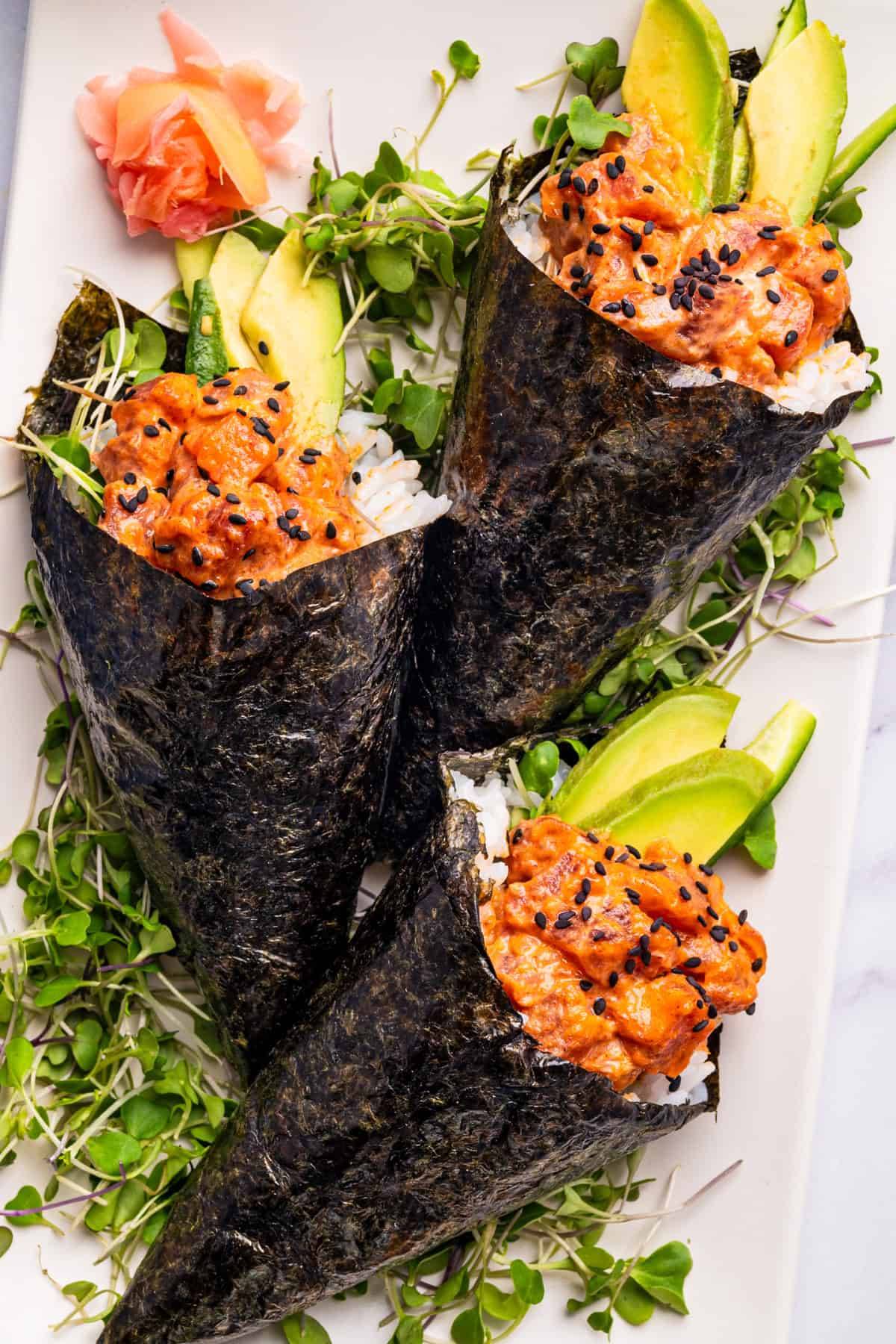 Spicy Tuna Hand Rolls with Avocado, Cucumber, and Rice on a plate.