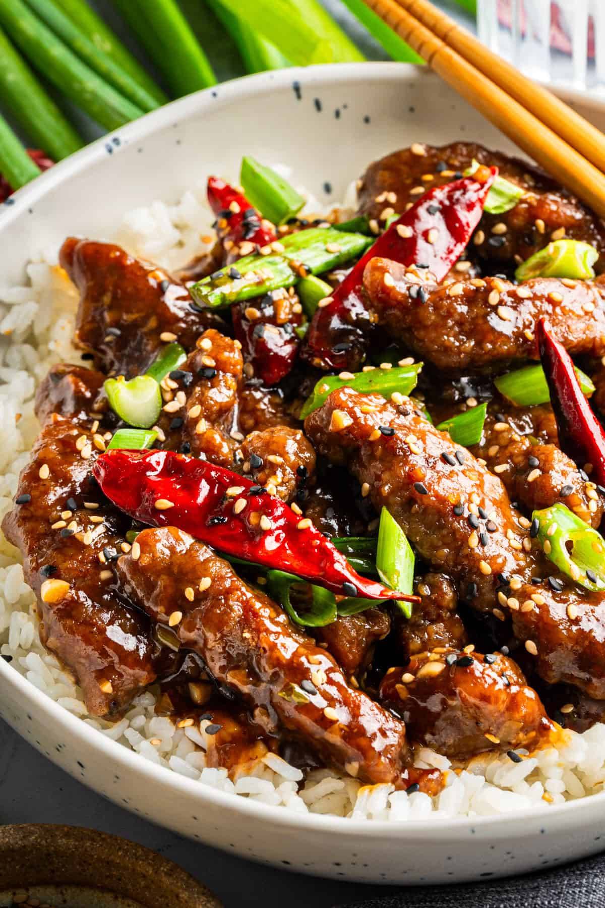 Mongolian Beef: tender flank steak, veggies, homemade glossy brown stir-fry sauce, and rice in a bowl.