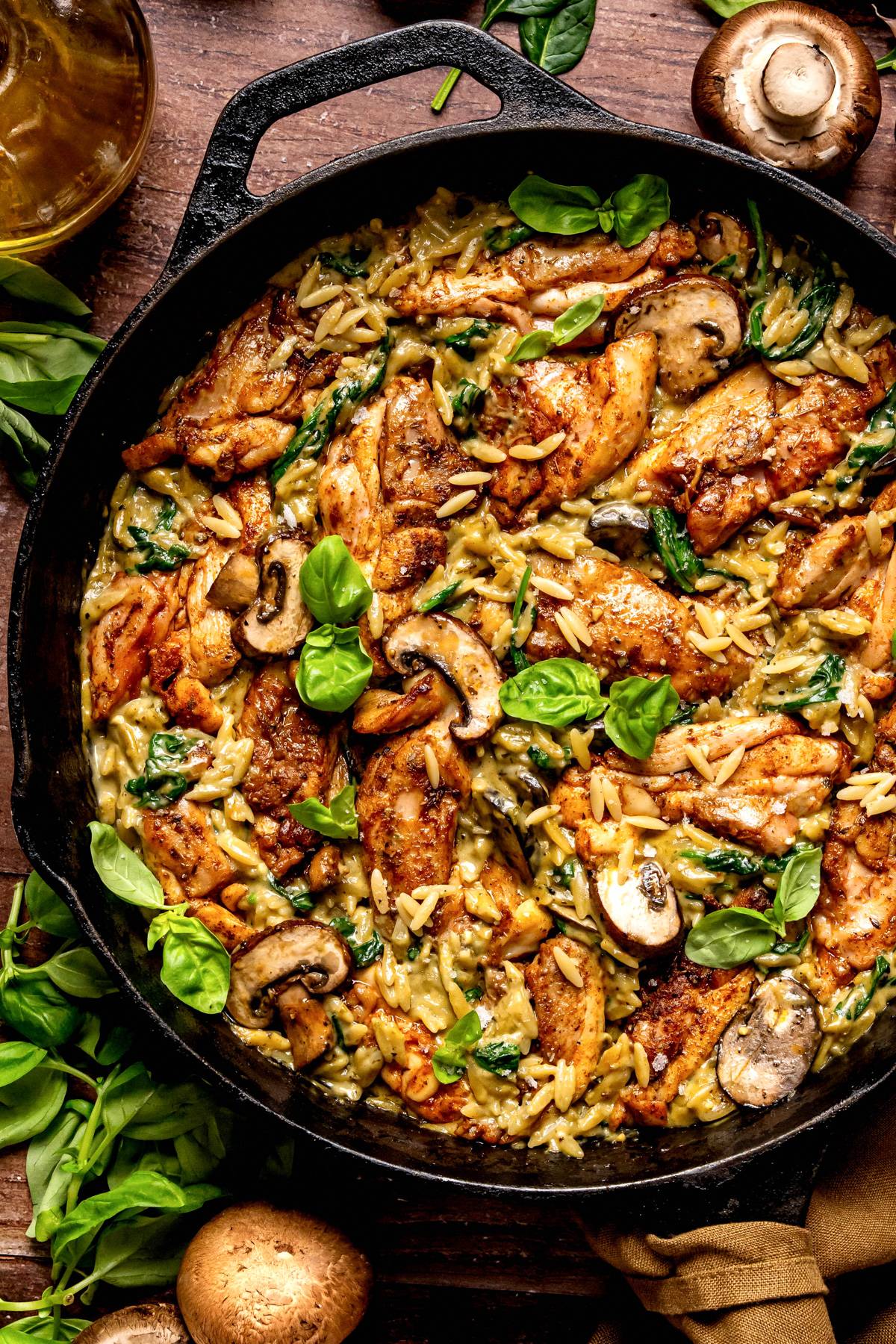 Creamy Chicken Orzo with Mushrooms, Spinach, and Basil Pesto in a cast iron pan.
