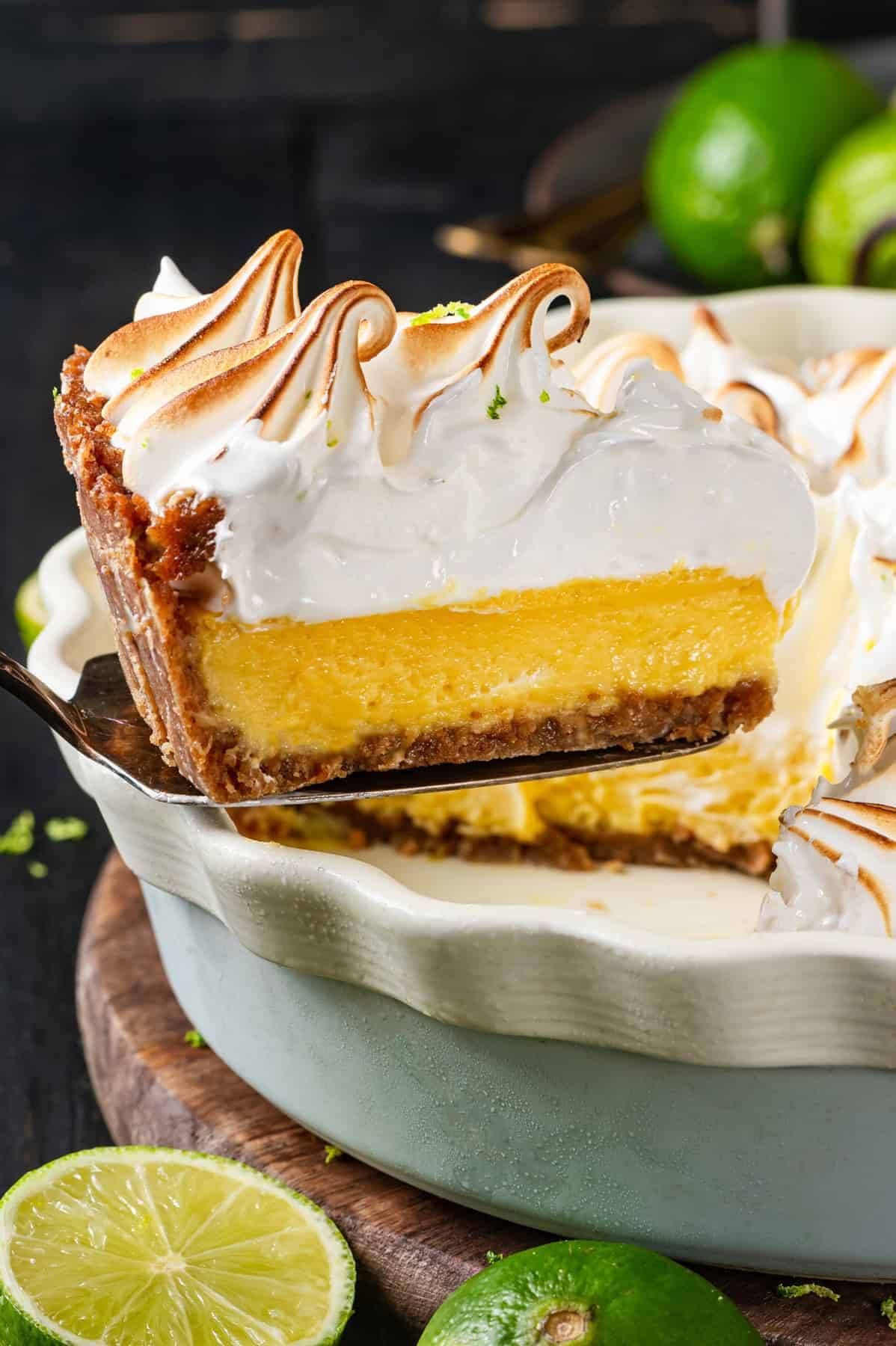 A slice of Key Lime Pie with Swiss Meringue on a spatula over a pie dish.