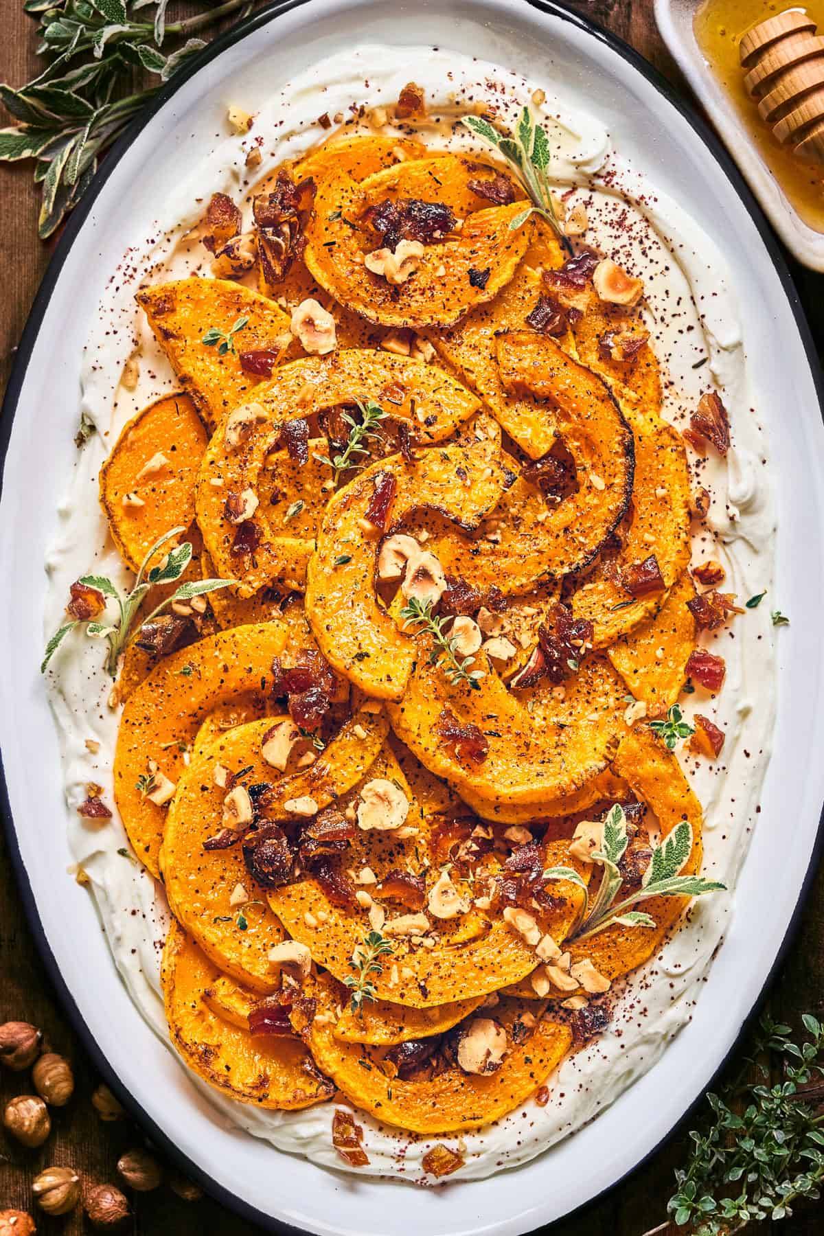 Roasted Butternut Squash with Honey Labneh (or Greek Yogurt), Dates, and Hazelnuts - on a long plate.