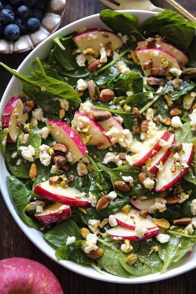 Apple Spinach Salad with Pistachios - in a white bowl.