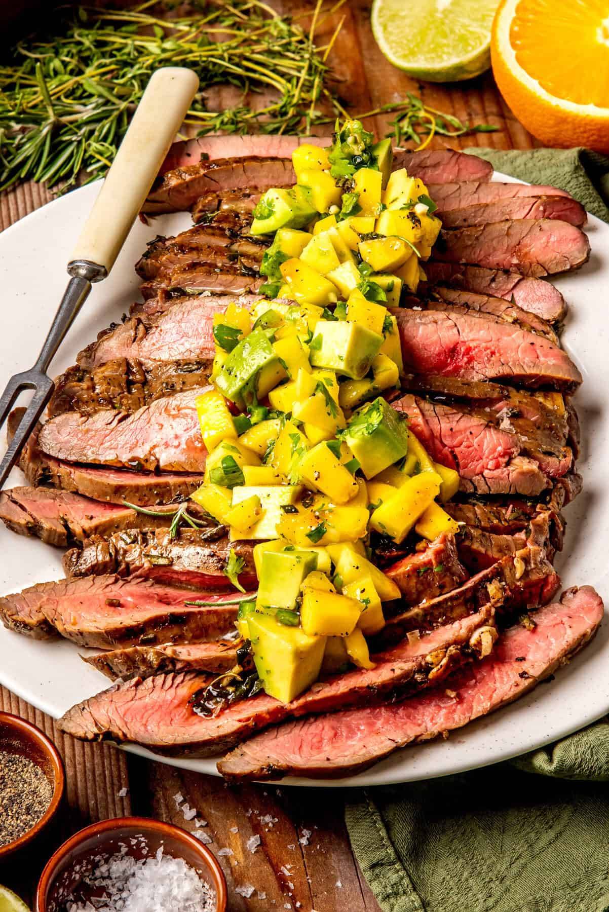 Grilled Flank Steak with Mango Avocado Salsa on a white plate.