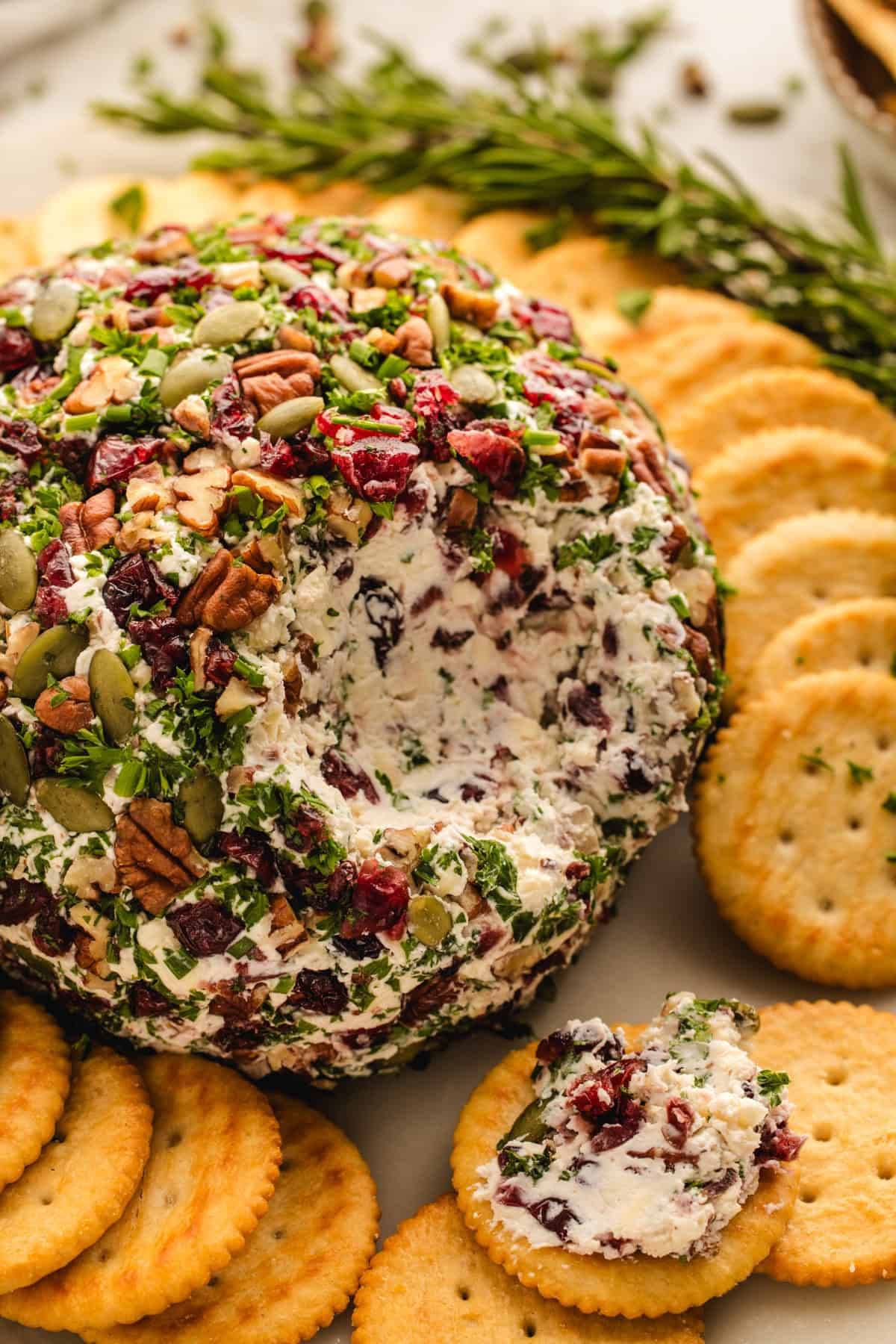 Cranberry Pecan Pumpkin Seed Cheese Ball on a plate with crackers.
