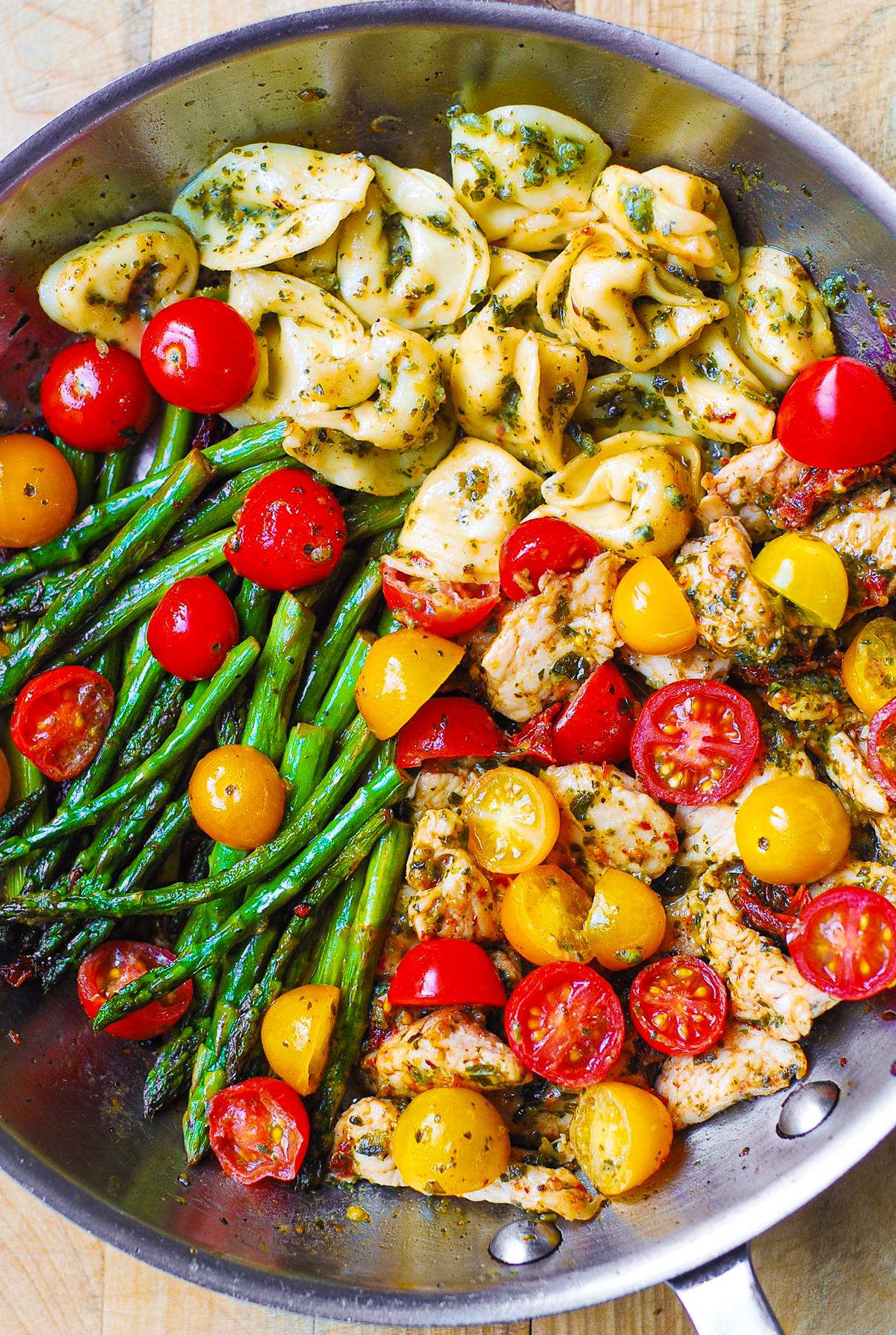 Pesto Chicken Tortellini & Veggies (Cherry Tomatoes and Aspragus) - in a stainless steel skillet.