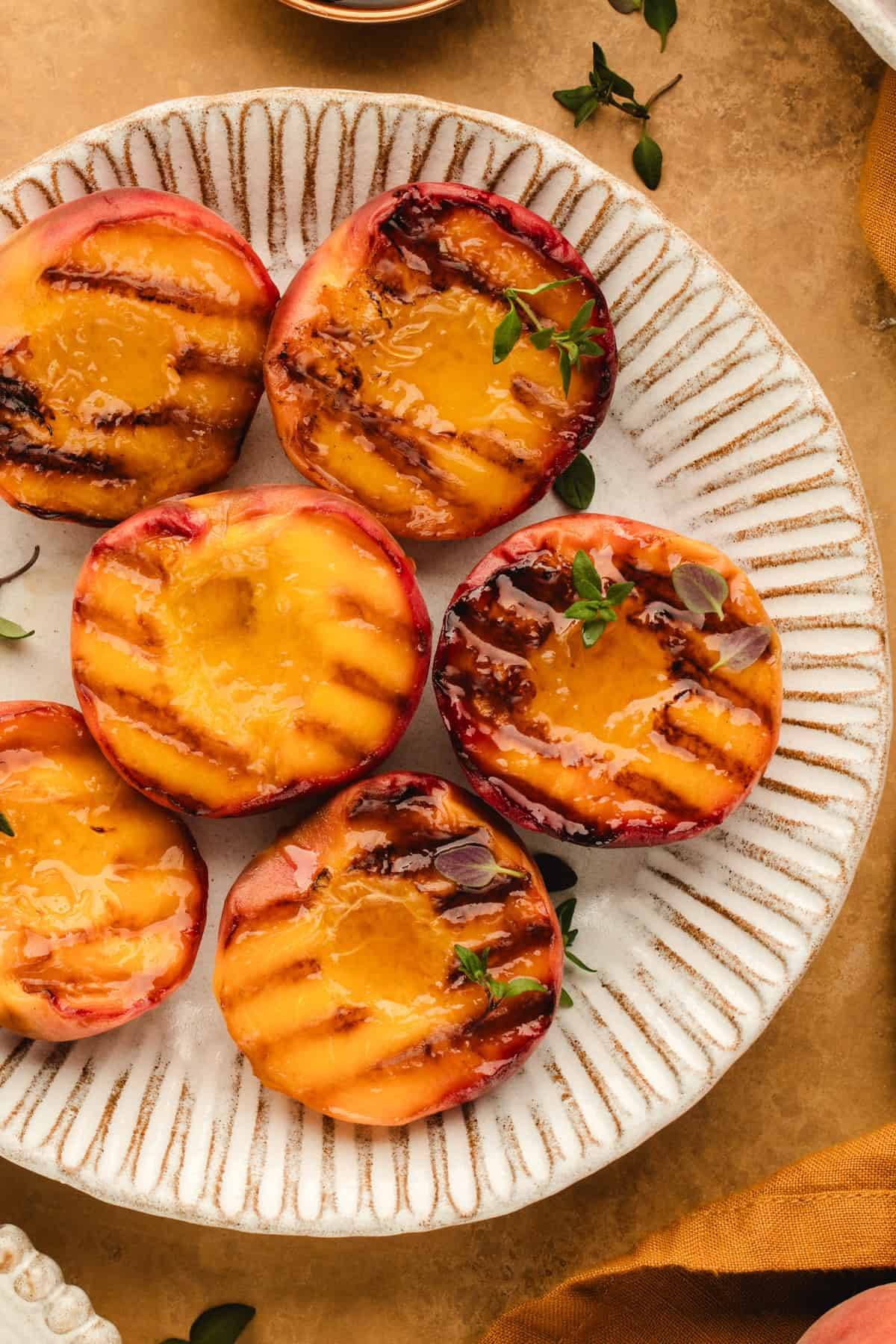 Grilled peach halves on a white plate.