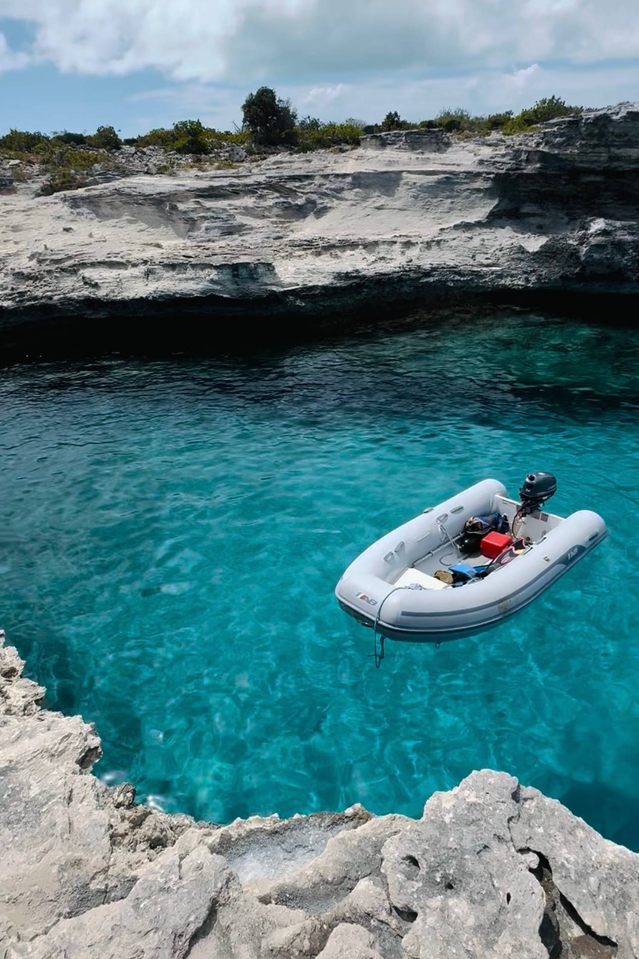 a small dinghy boat in the ocean by the rocks.