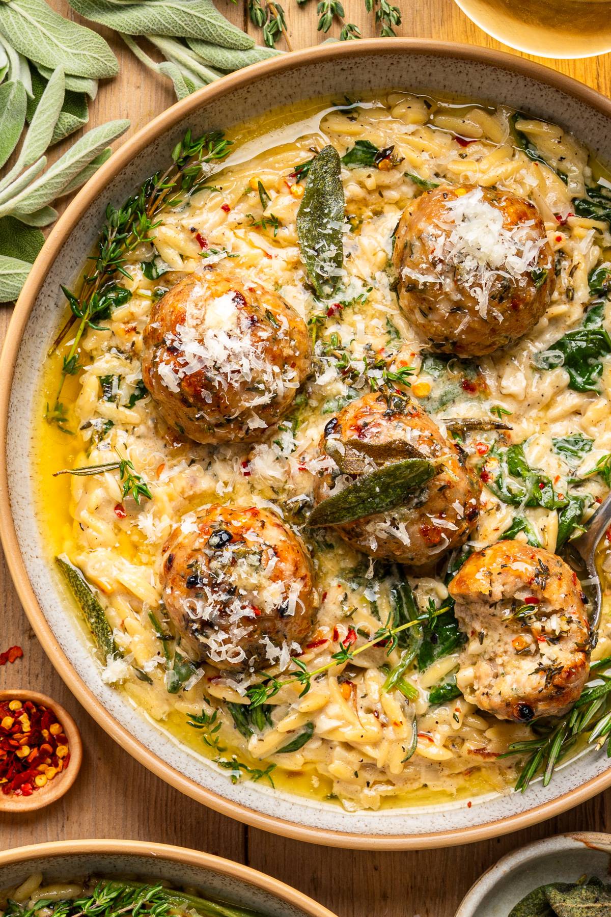 Baked Chicken Meatballs with Creamy Parmesan Spinach Orzo and Garlic-Butter-White-Wine Sauce - on a plate.