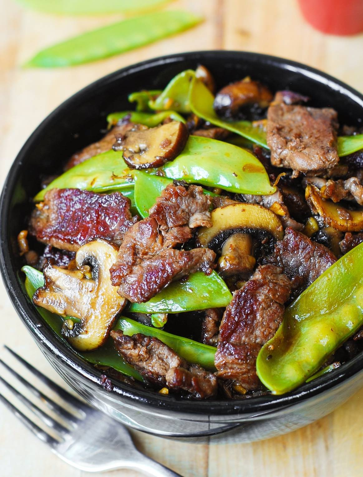 Asian Beef with Mushrooms and Snow Peas - in a black bowl.