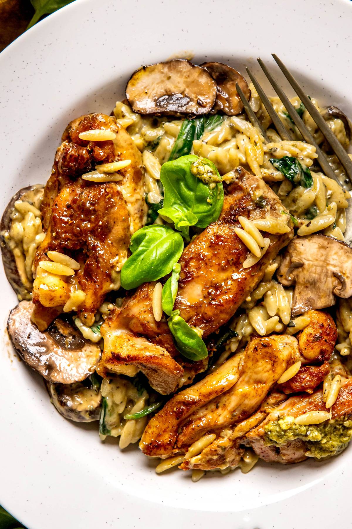 One-Pan Creamy Chicken Orzo with Mushrooms and Spinach in a white bowl.