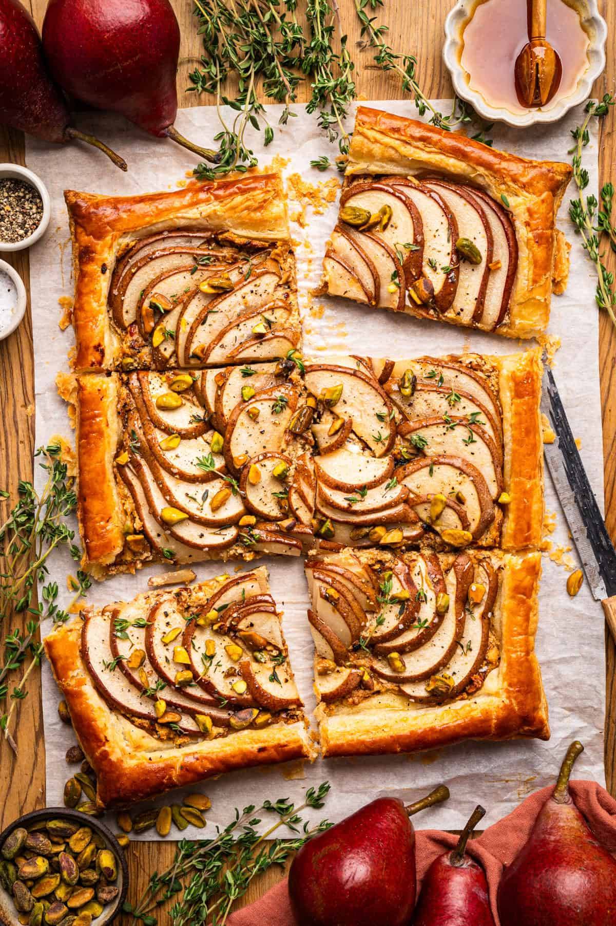 Flaky Puff Pastry Tart with Pears, Goat Cheese, and Pistachios on a white parchment paper.