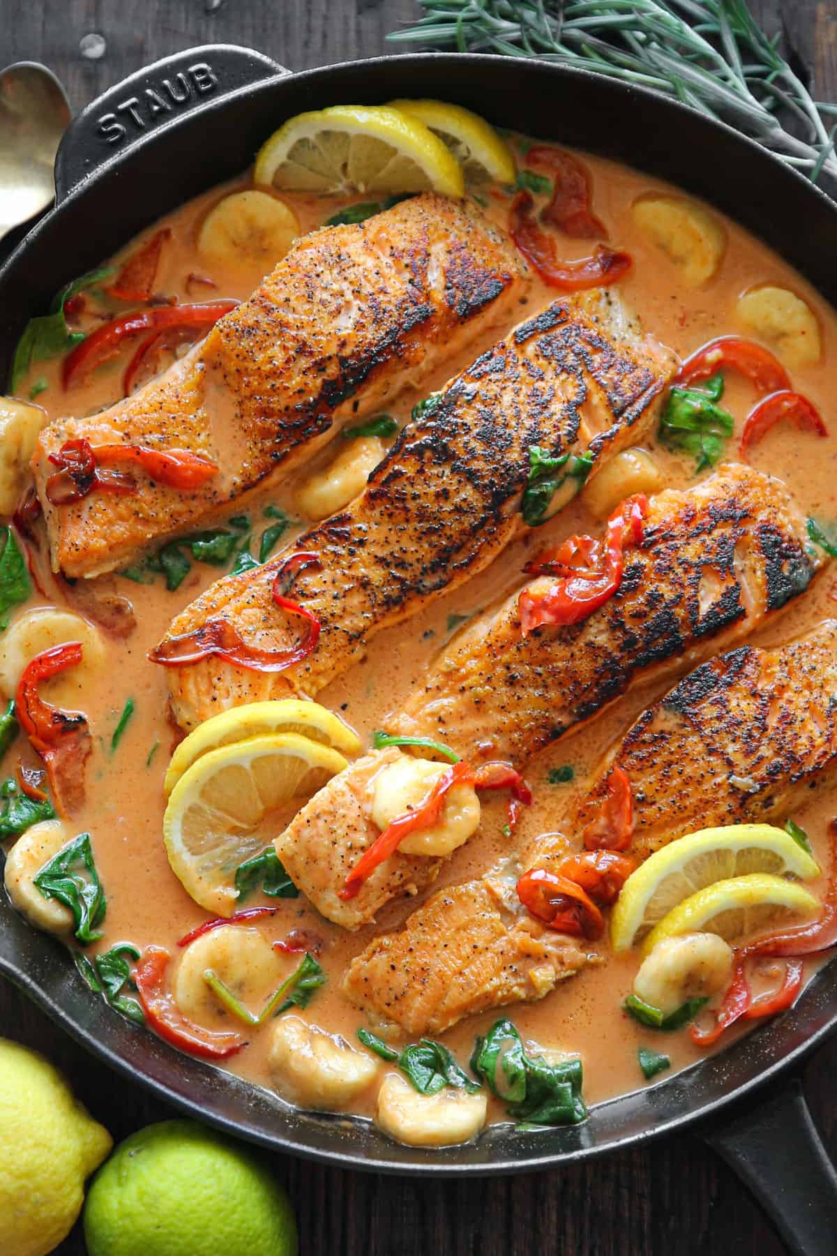 Thai Coconut Curry Salmon with bell peppers, spinach, and sliced bananas - in a cast iron skillet. 