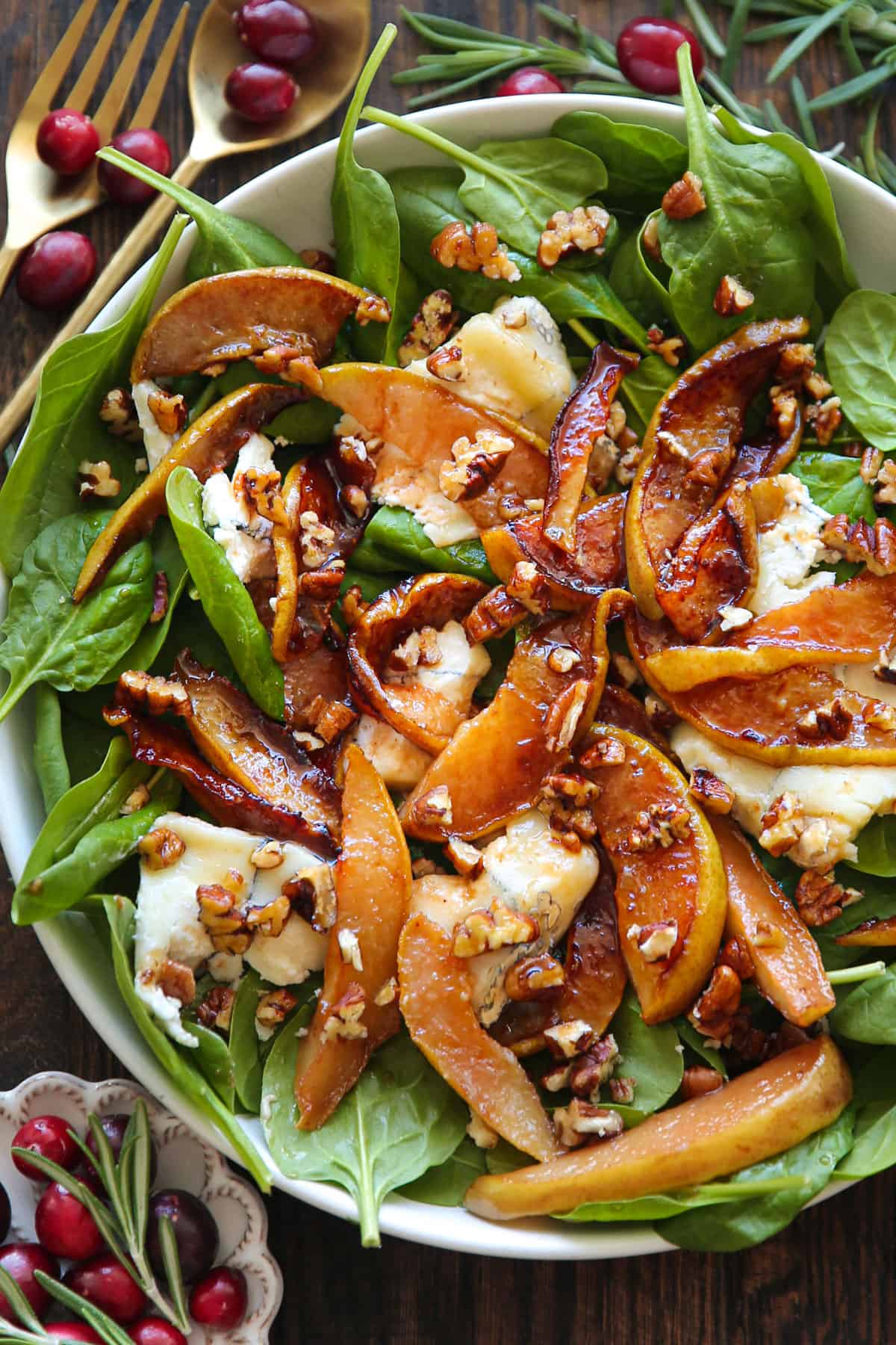 Pear Spinach Salad with Goat Cheese, Pecans, and Honey-Lemon Dressing in a white bowl.