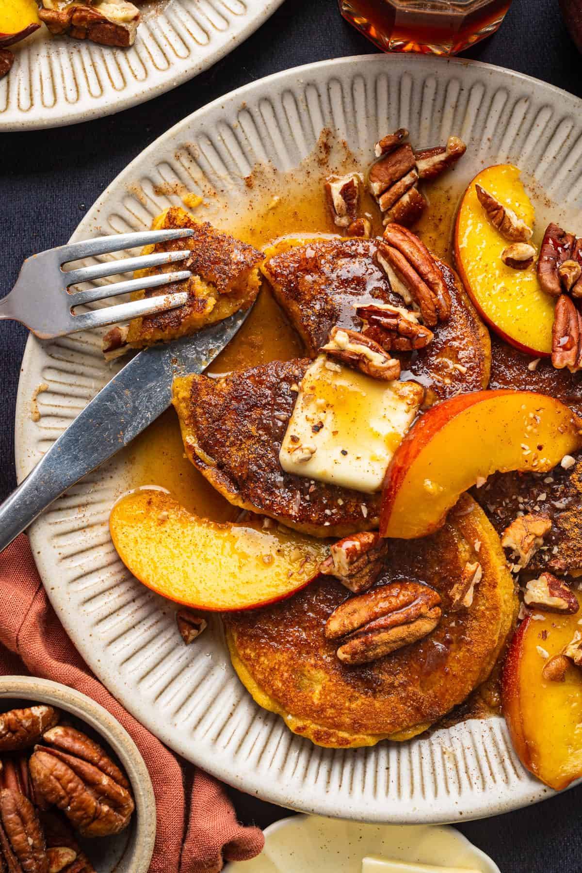 Peach Pancakes with Pecans and Cinnamon Maple Syrup on a large white plate.