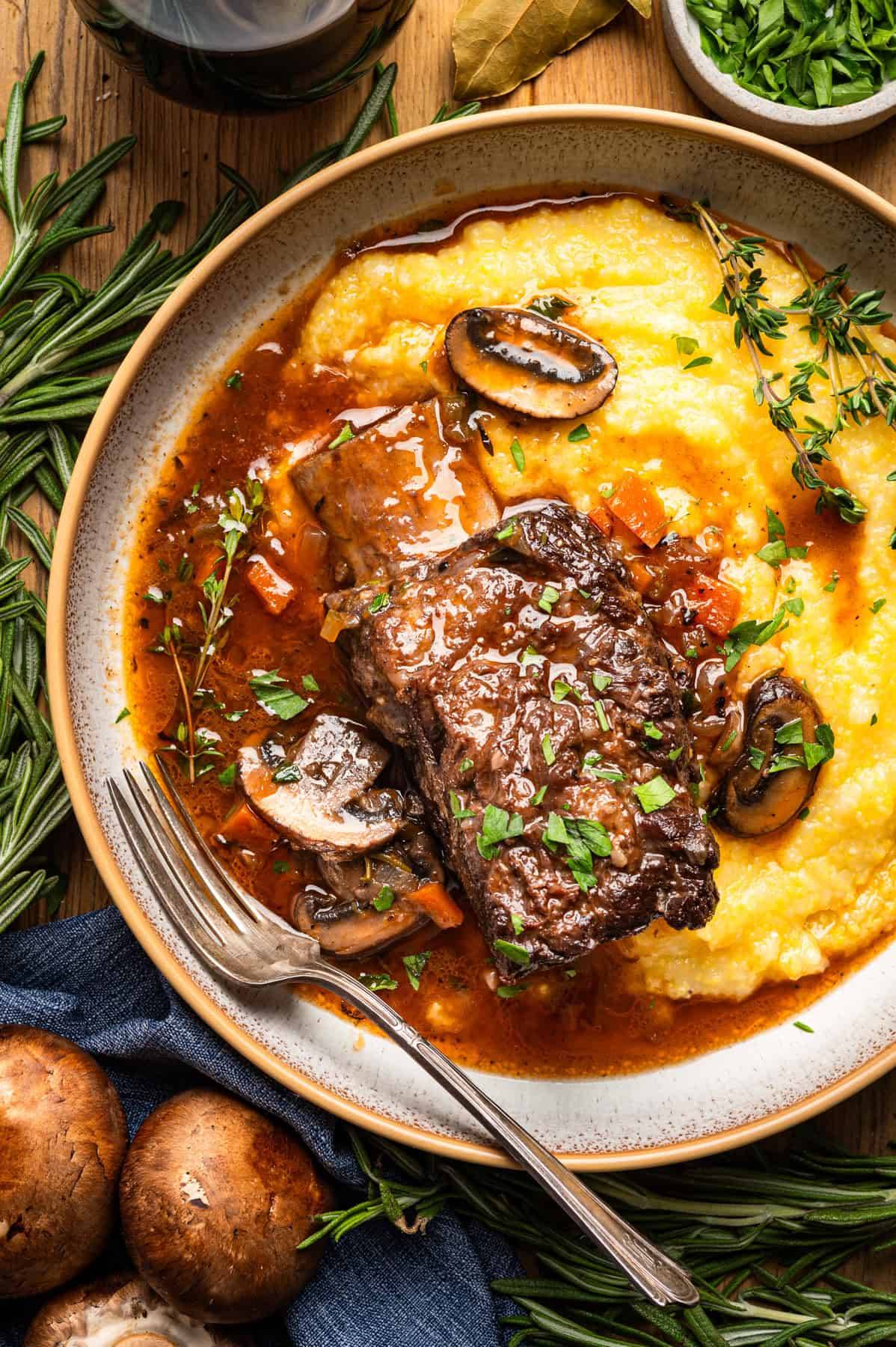 Braised Short Ribs with Polenta, Mushrooms, and Red Wine Sauce in a bowl.